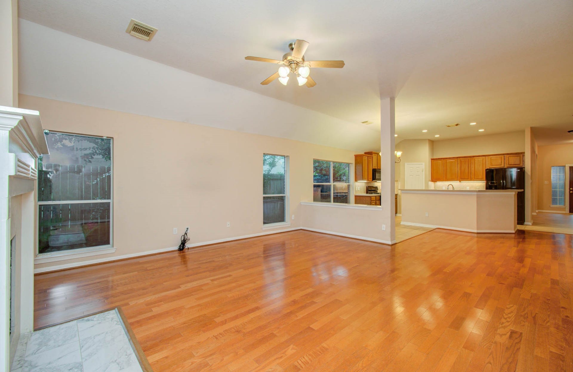 14403 Red Tailed Hawk Lane, Houston, TX 77044 Spacious open-concept living area with warm hardwood floors, a cozy fireplace, and a modern kitchen featuring a large breakfast bar and sleek appliances. Abundant natural light enhances the welcoming atmosphere.