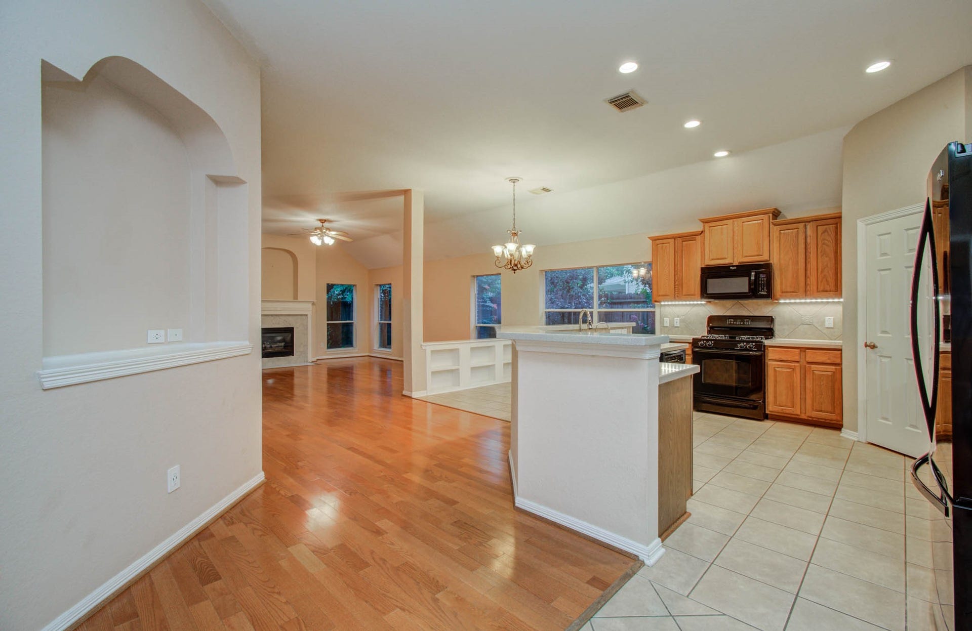 14403 Red Tailed Hawk Lane, Houston, TX 77044 Spacious open-concept kitchen and living area featuring warm hardwood floors, a cozy fireplace, and abundant natural light. The kitchen boasts modern appliances, ample cabinetry, and a convenient breakfast bar.