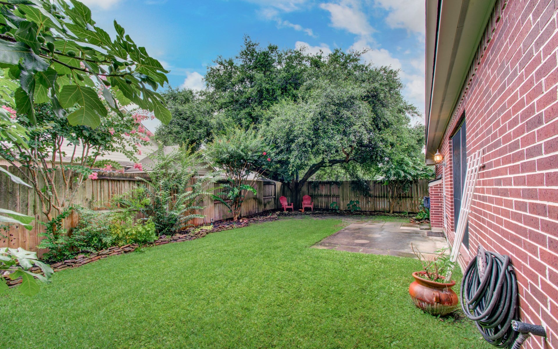 14403 Red Tailed Hawk Lane, Houston, TX 77044 Charming backyard with lush green lawn, mature trees, and a cozy patio perfect for relaxing.