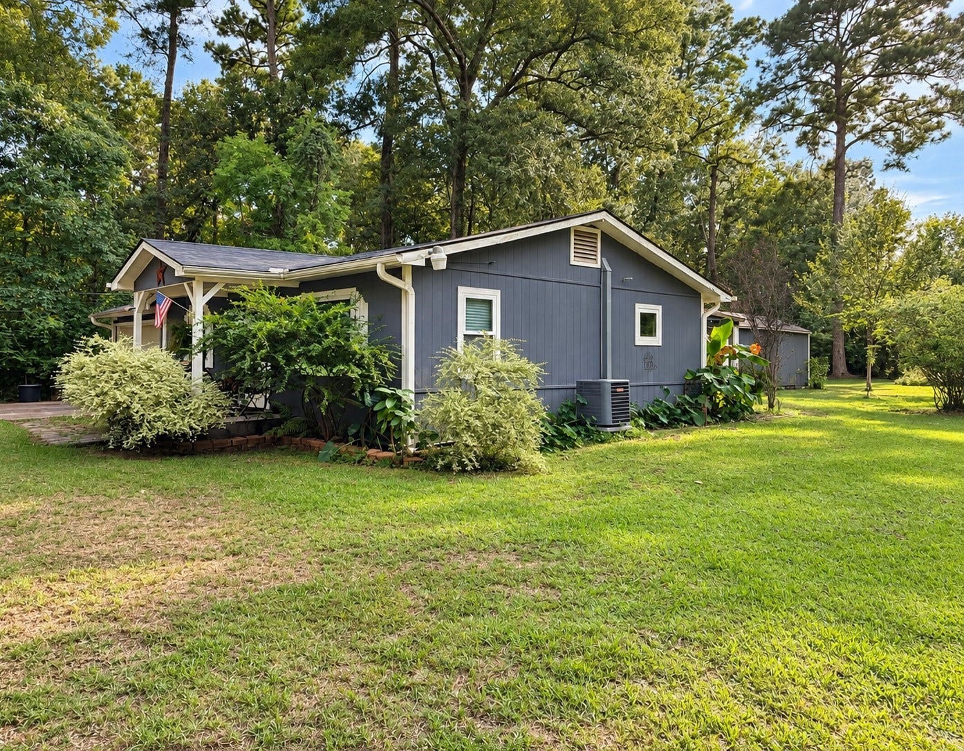 14440 Lakecrest Drive, Splendora, TX 77372 Front Exterior Charming exterior with updated blue siding, covered entry, mature landscaping and spacious lawn.