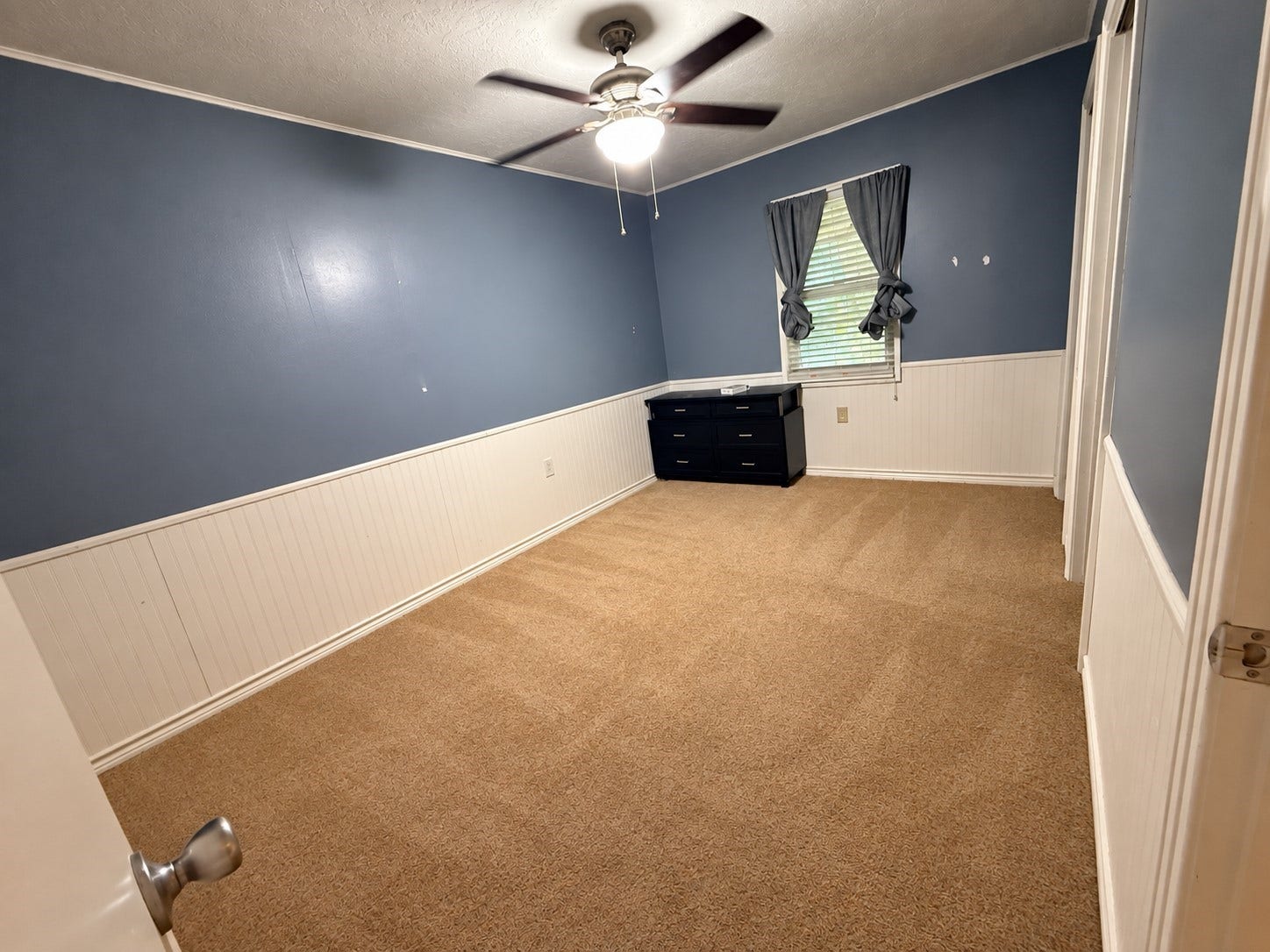 14440 Lakecrest Drive, Splendora, TX 77372 Spacious bedroom with neutral carpet, beadboard wainscoting, ceiling fan, and natural light.
