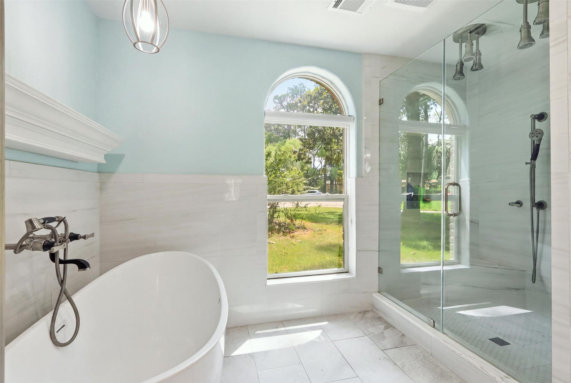 6518 Elmgrove Road, Spring, TX 77389 Spa-like primary bath featuring a freestanding soaking tub and oversized glass-enclosed shower with multiple shower heads.