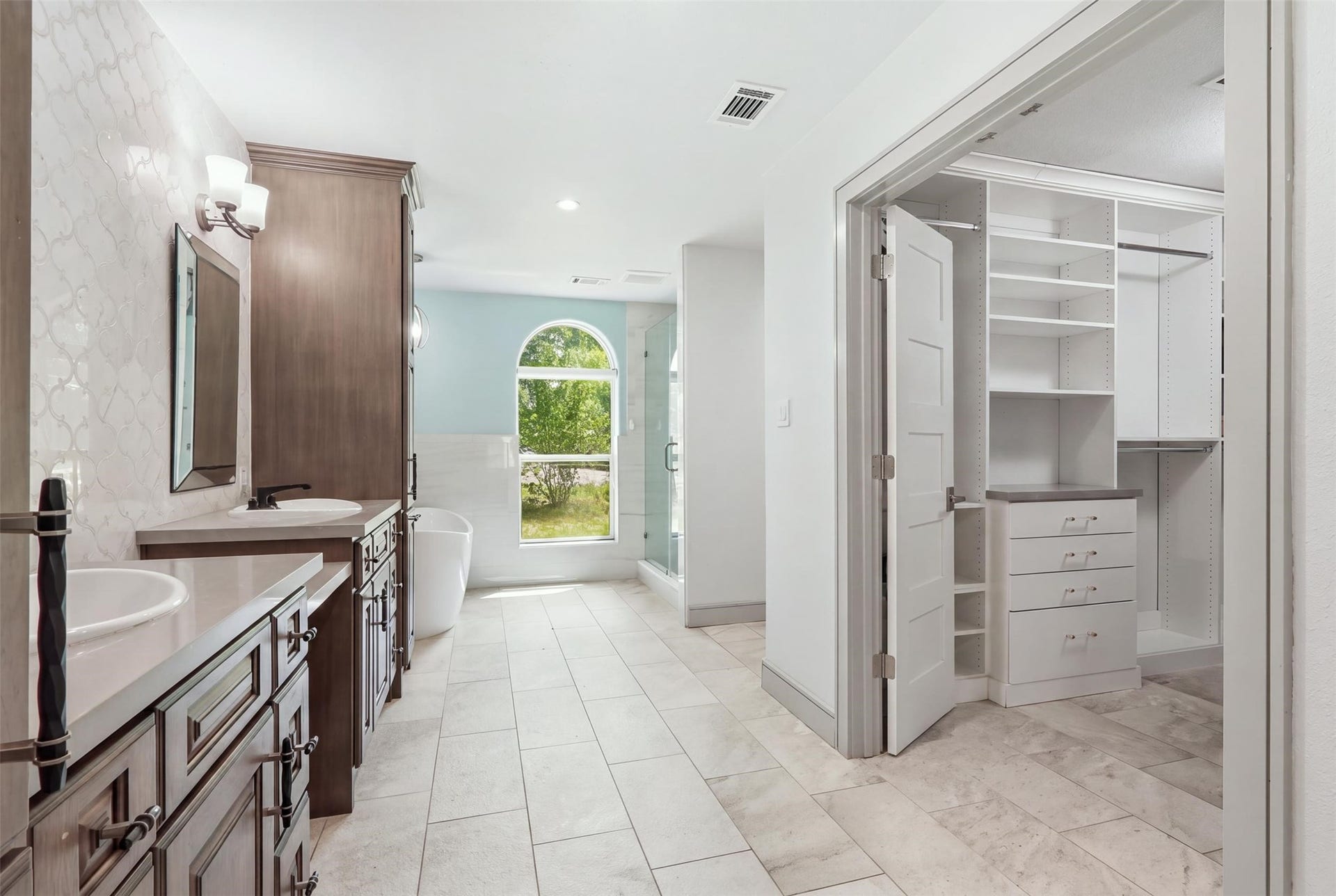 6518 Elmgrove Road, Spring, TX 77389 Spa-like primary bath featuring dual vanities, a freestanding soaking tub, walk-in shower, and spacious custom closet.