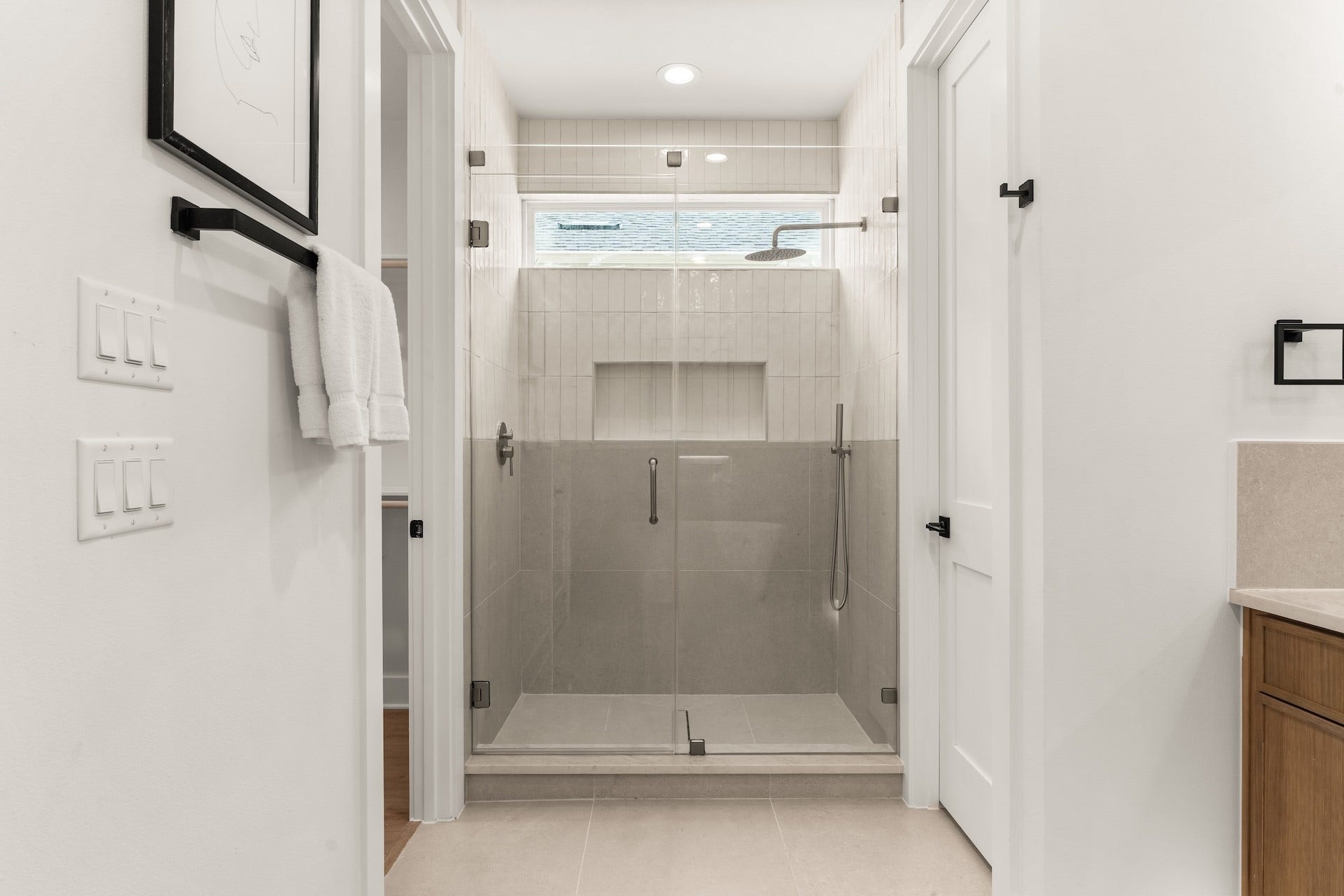 Spa-inspired primary shower featuring frameless glass, custom tilework, and dual shower heads.