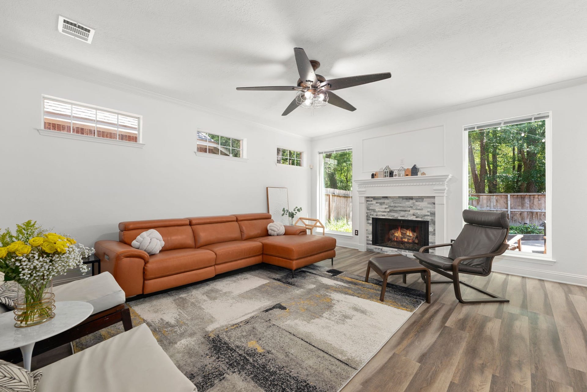 26 Cinnamon Teal Place, The Woodlands, TX 77382 Spacious living room featuring a cozy fireplace, elegant wood fllooring, and abundant natural light from large windows.