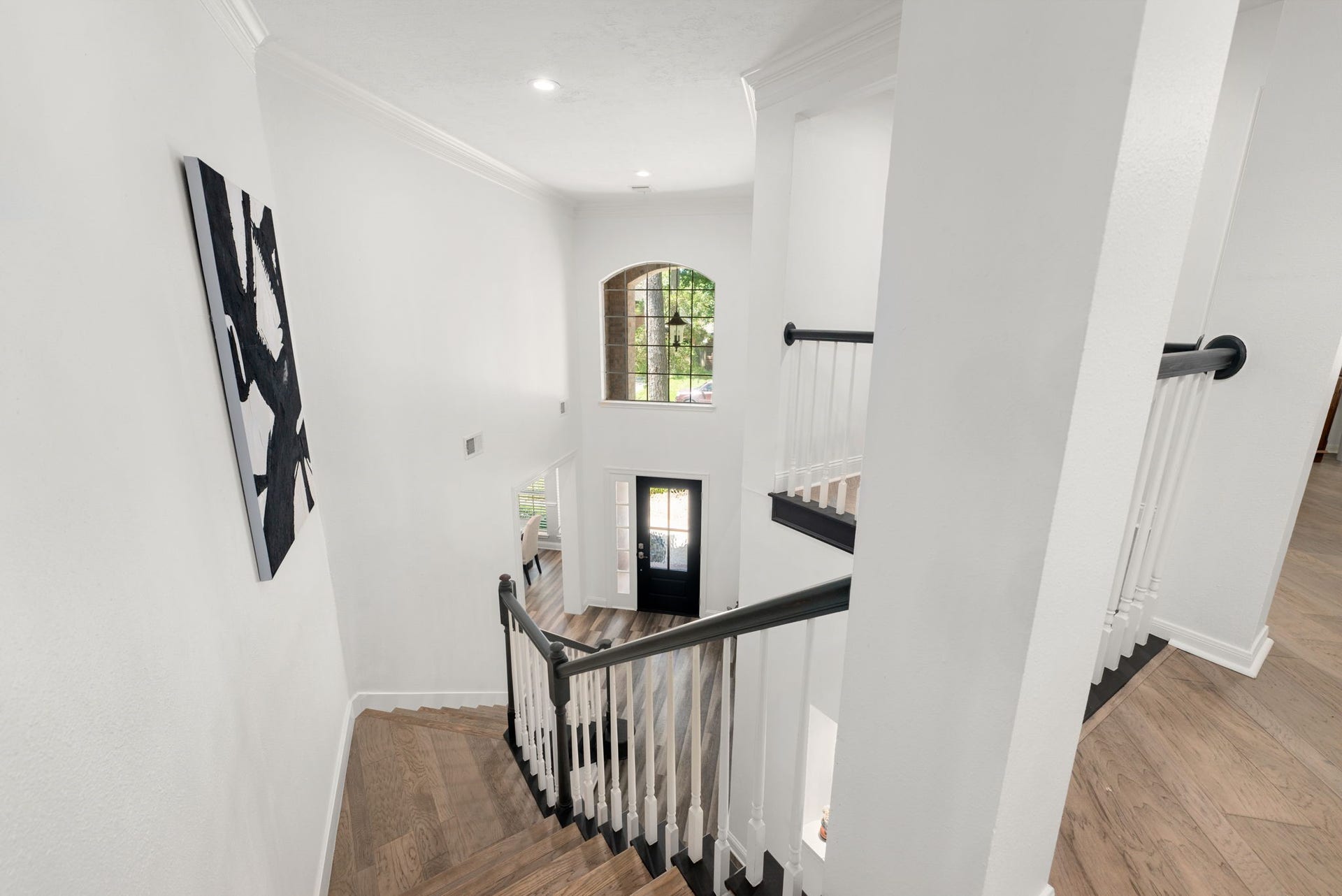 26 Cinnamon Teal Place, The Woodlands, TX 77382 Elegant staircase with rich wood flooring and sleek white railings.