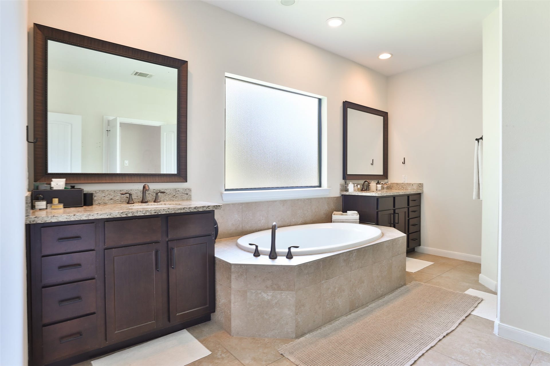 1112 Bingham Street, Houston, TX 77007 Luxurious bathroom featuring a central soaking tub, elegant dark wood vanities with granite countertops, and soft natural lighting for a serene spa-like atmosphere.