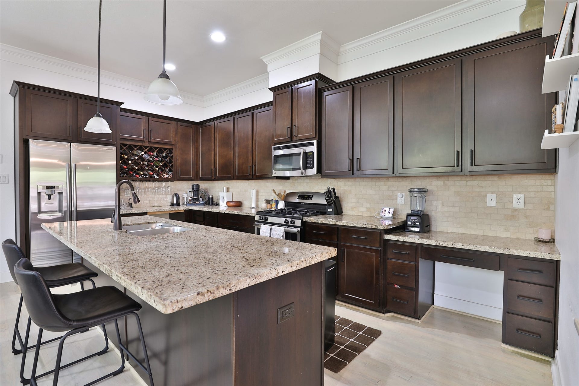 1112 Bingham Street, Houston, TX 77007 Elegant kitchen featuring rich dark wood cabinets, sleek stainless steel appliances, and a spacious granite island with seating for casual dining.