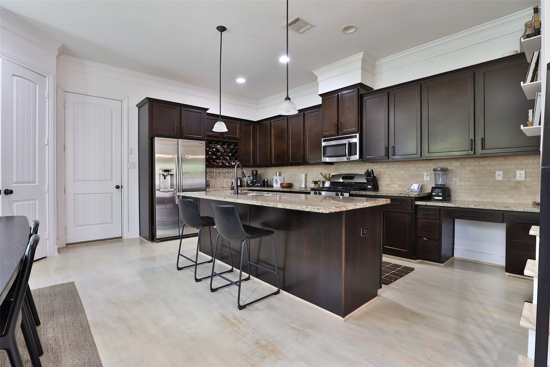 1112 Bingham Street, Houston, TX 77007 Elegant kitchen with dark wood cabinetry, a spacious granite island, and modern stainless steel appliances, perfect for culinary enthusiasts.