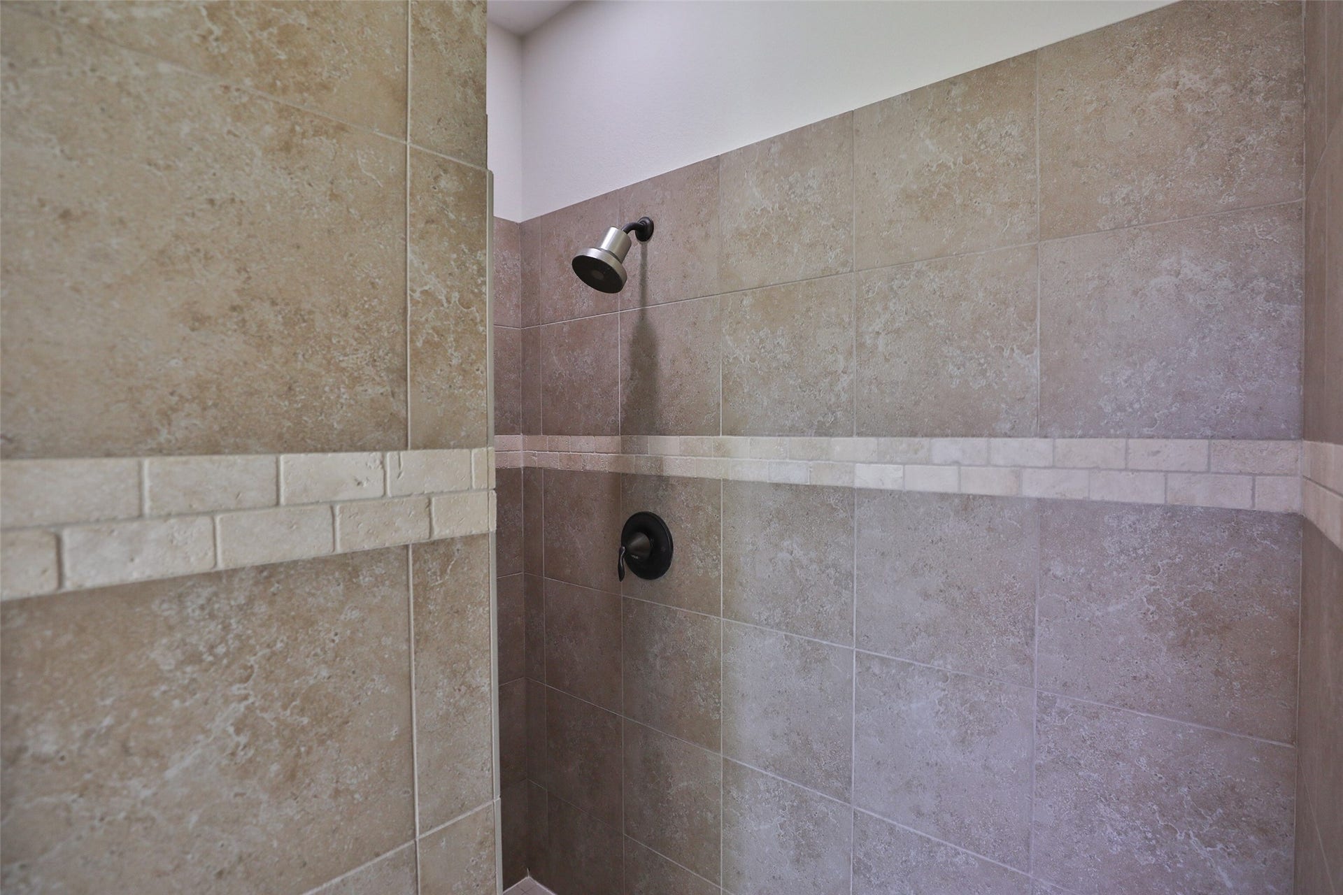 1112 Bingham Street, Houston, TX 77007 Elegant shower with neutral-toned tiles and a modern showerhead, providing a serene and stylish bathing experience.