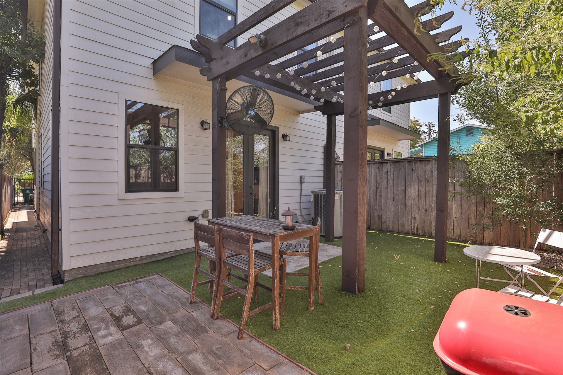 1112 Bingham Street, Houston, TX 77007 Charming backyard retreat features a rustic pergola over a cozy seating area, perfect for outdoor dining and relaxation, complemented by a low-maintenance artificial turf and privacy fencing.