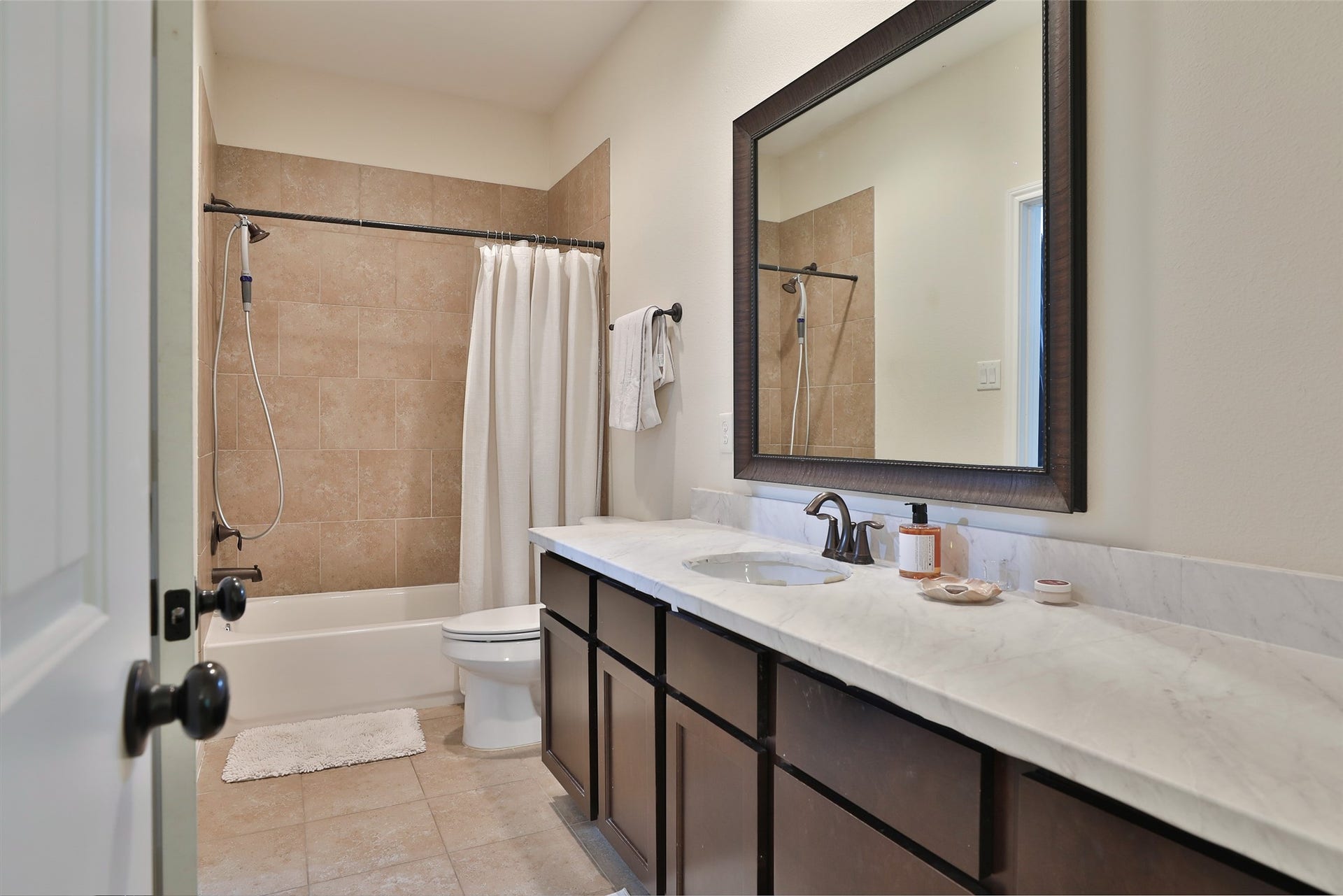 1112 Bingham Street, Houston, TX 77007 Modern bathroom featuring a spacious vanity with a marble countertop, large framed mirror, and a combined shower-tub with elegant tile work.