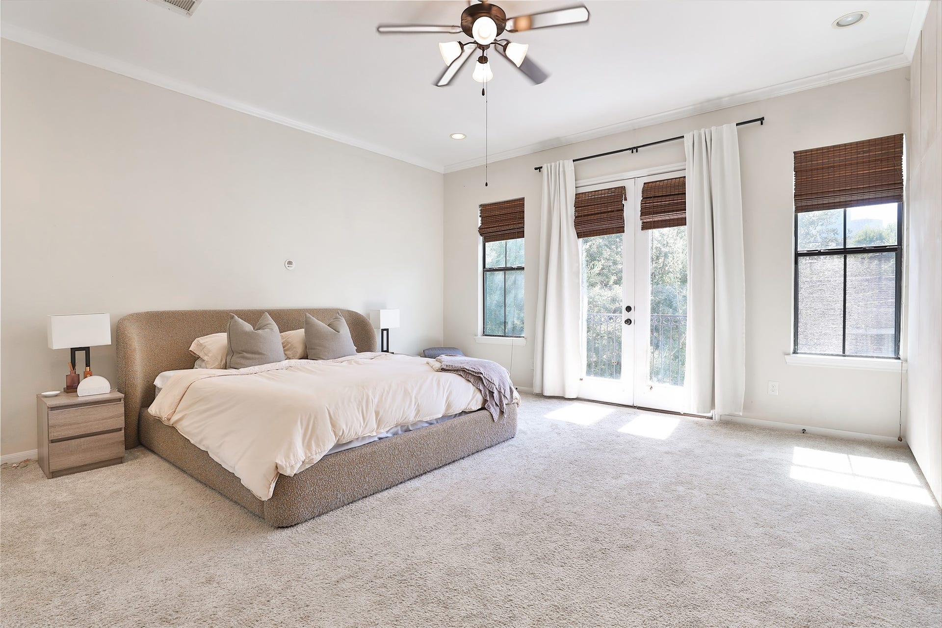 1112 Bingham Street, Houston, TX 77007 Spacious and bright bedroom featuring a plush bed, soft carpeting, and large windows with elegant curtains, offering abundant natural light and serene views.