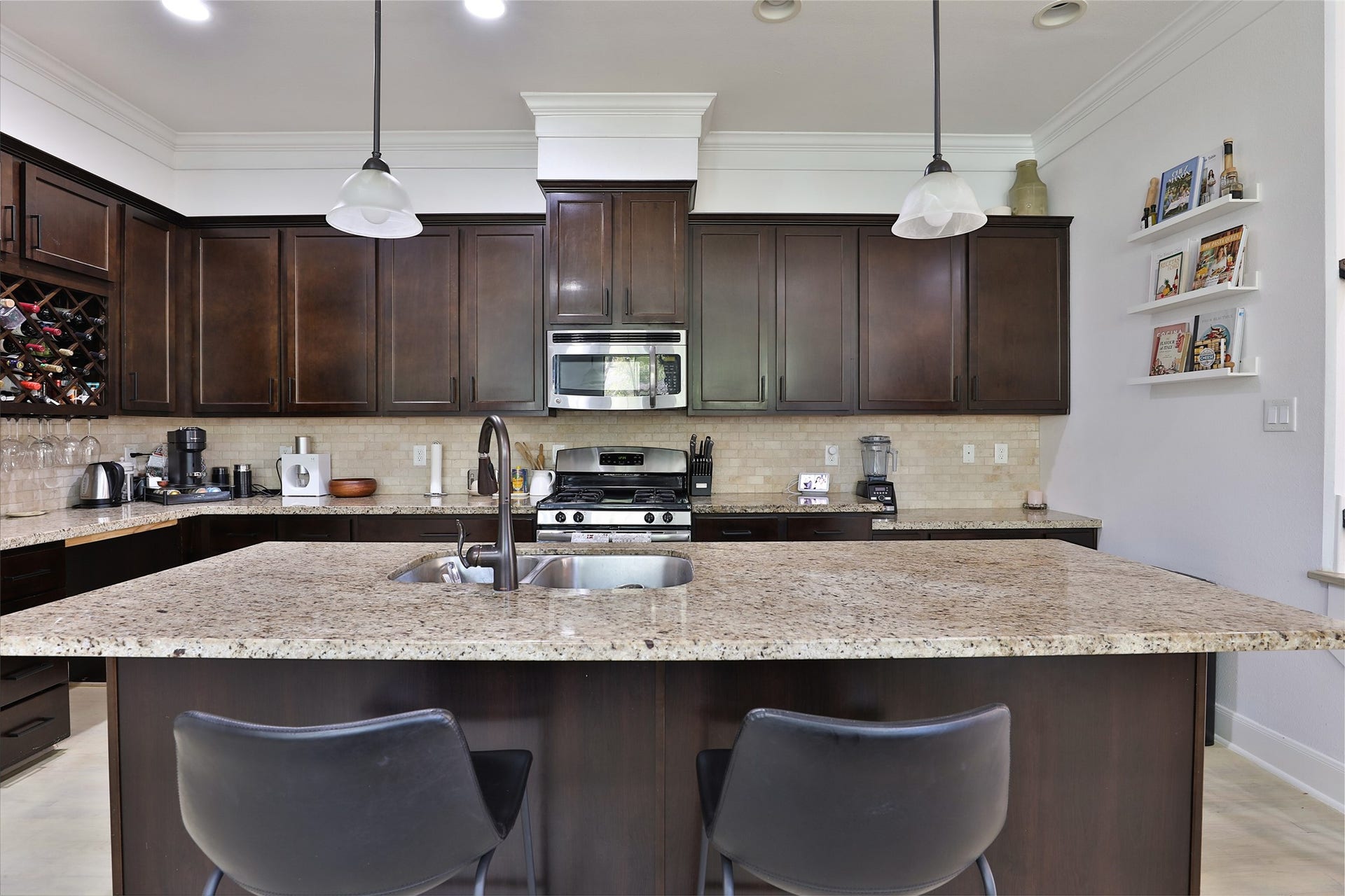 1112 Bingham Street, Houston, TX 77007 Spacious kitchen with dark wood cabinetry, granite countertops, and stainless steel appliances, featuring a central island with seating and pendant lighting.