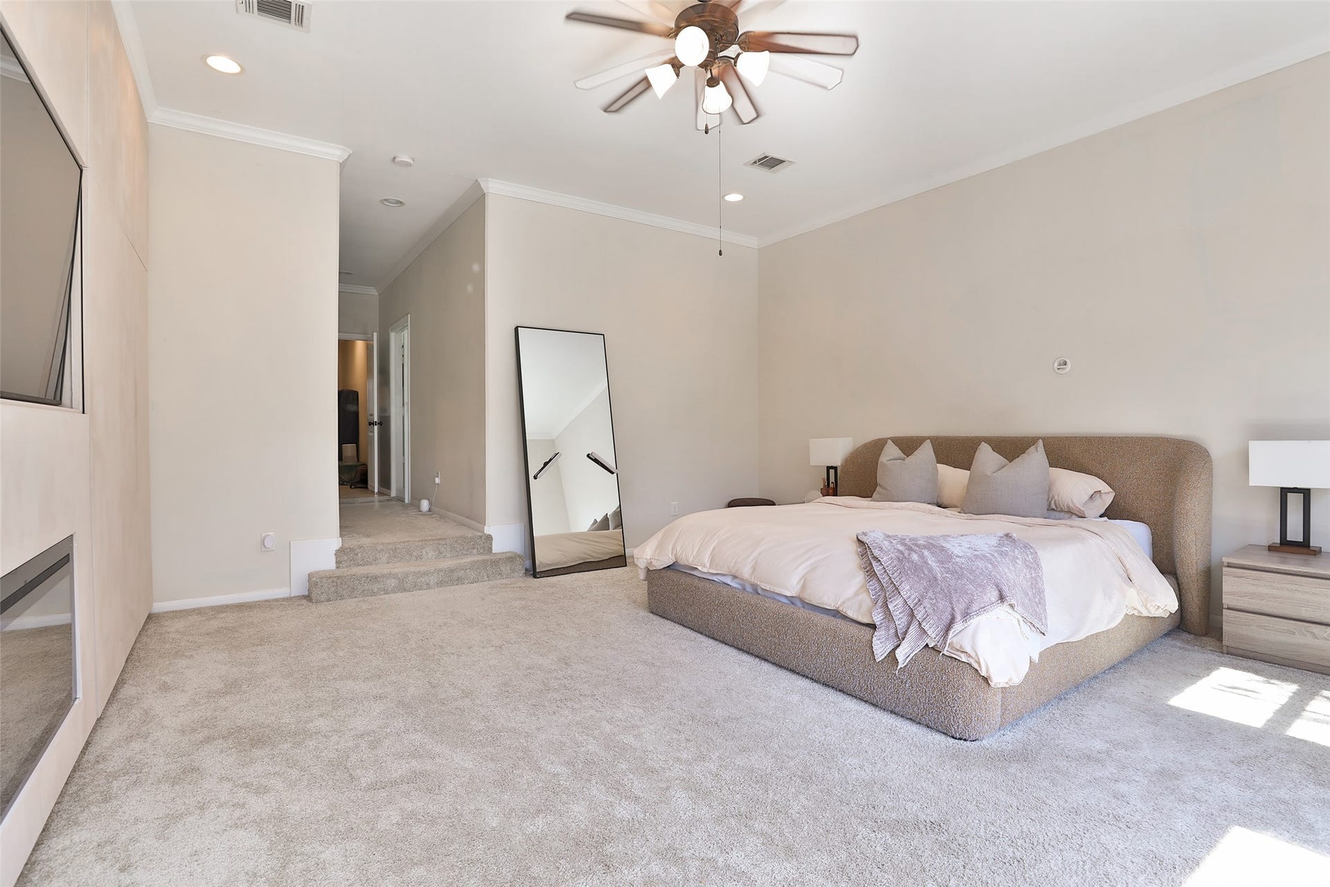 1112 Bingham Street, Houston, TX 77007 Spacious and elegant bedroom featuring plush carpeting, a modern ceiling fan, and a cozy bed with neutral tones, complemented by natural light and a sleek wall-mounted TV.