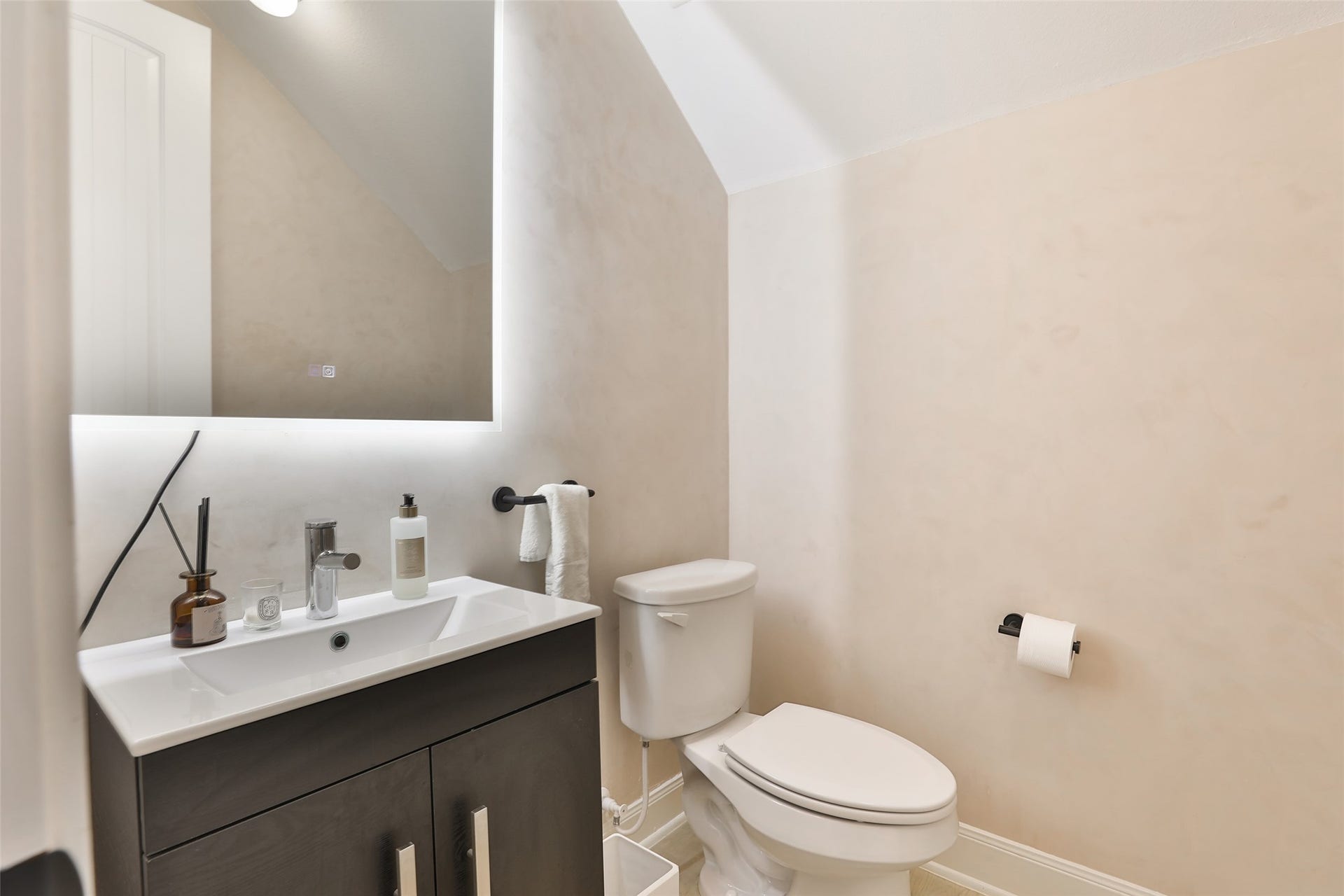 1112 Bingham Street, Houston, TX 77007 Chic and modern half-bathroom featuring a sleek vanity with ample storage, complemented by a large illuminated mirror and subtle, elegant decor.