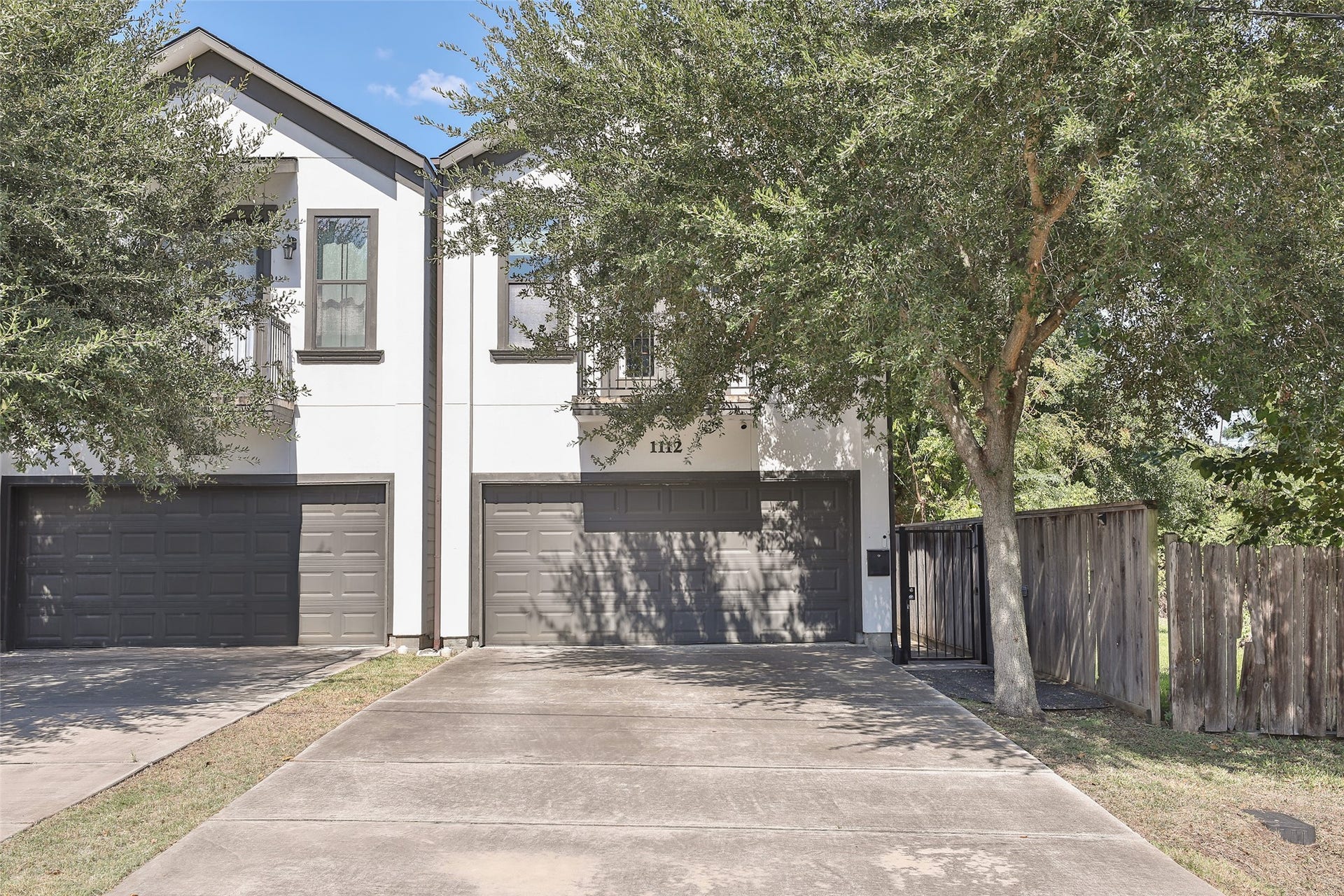1112 Bingham Street, Houston, TX 77007 Chic modern townhouse with a sleek two-car garage, framed by mature trees and a private fenced yard, offering both style and seclusion.