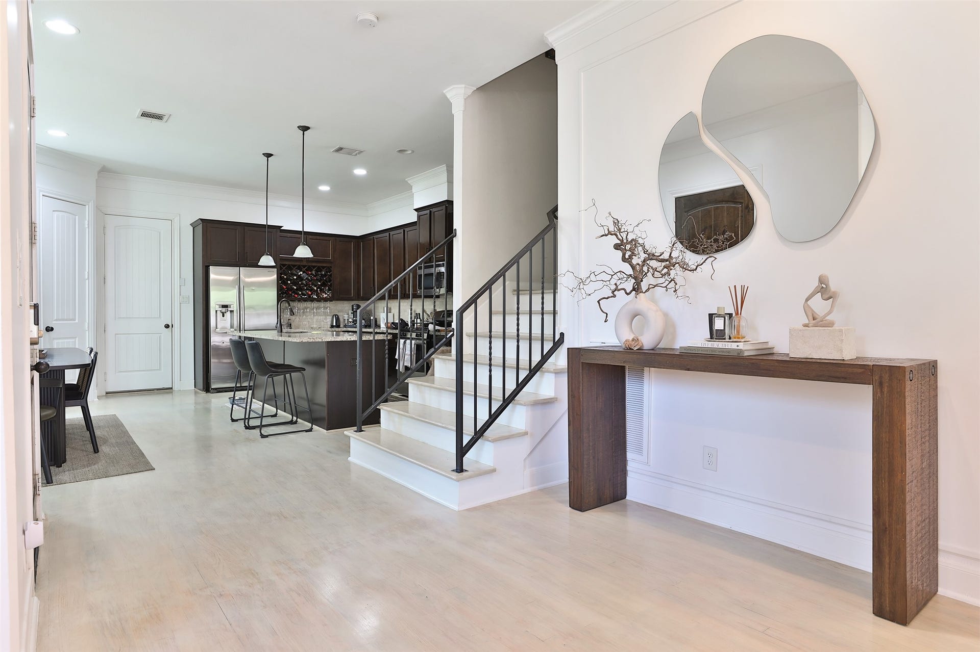 1112 Bingham Street, Houston, TX 77007 Chic and contemporary entryway leads to a modern kitchen with dark cabinetry, stainless steel appliances, and a stylish breakfast bar.