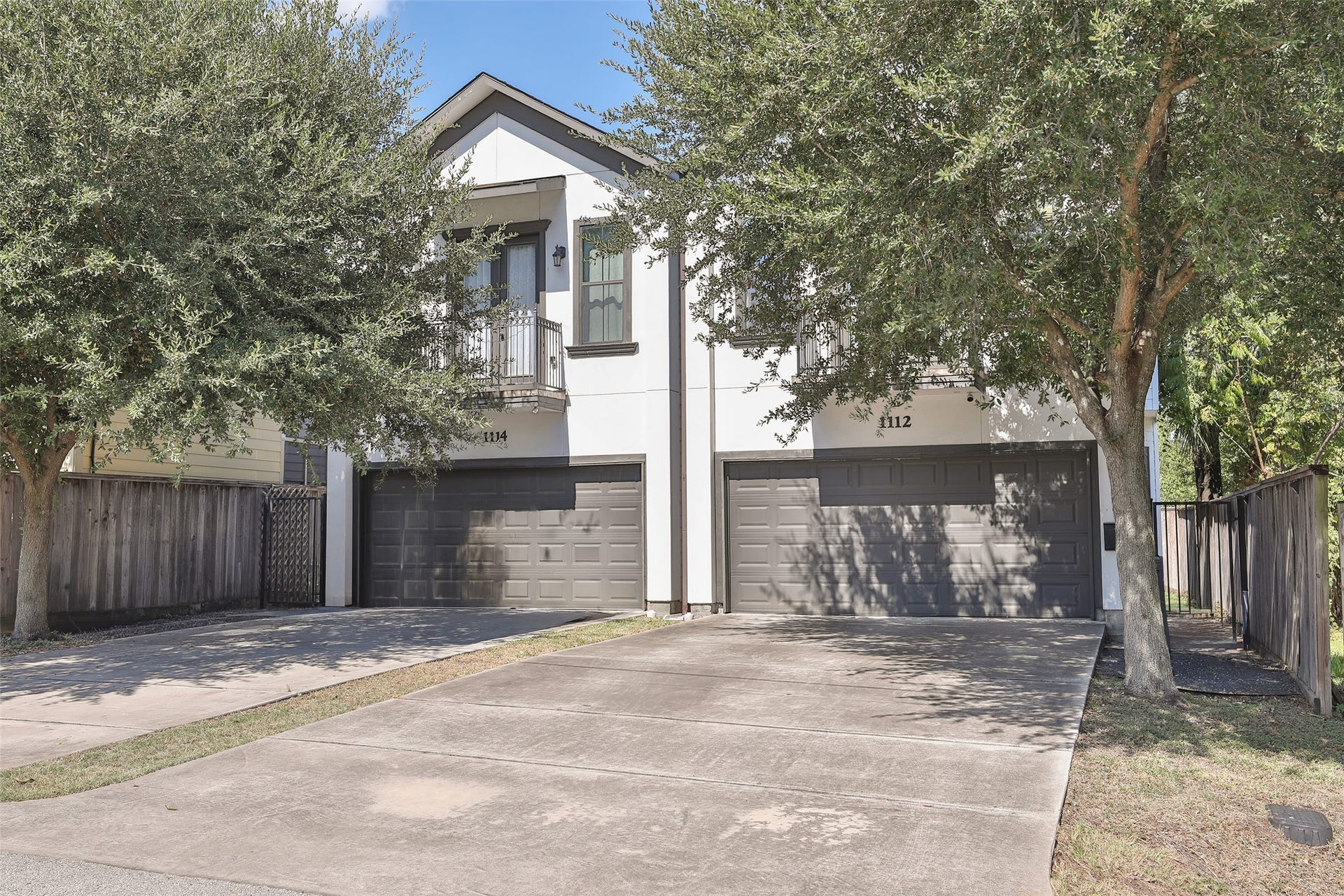 1112 Bingham Street, Houston, TX 77007 Modern duplex with a sleek exterior, featuring a double garage and mature trees providing shade and privacy.