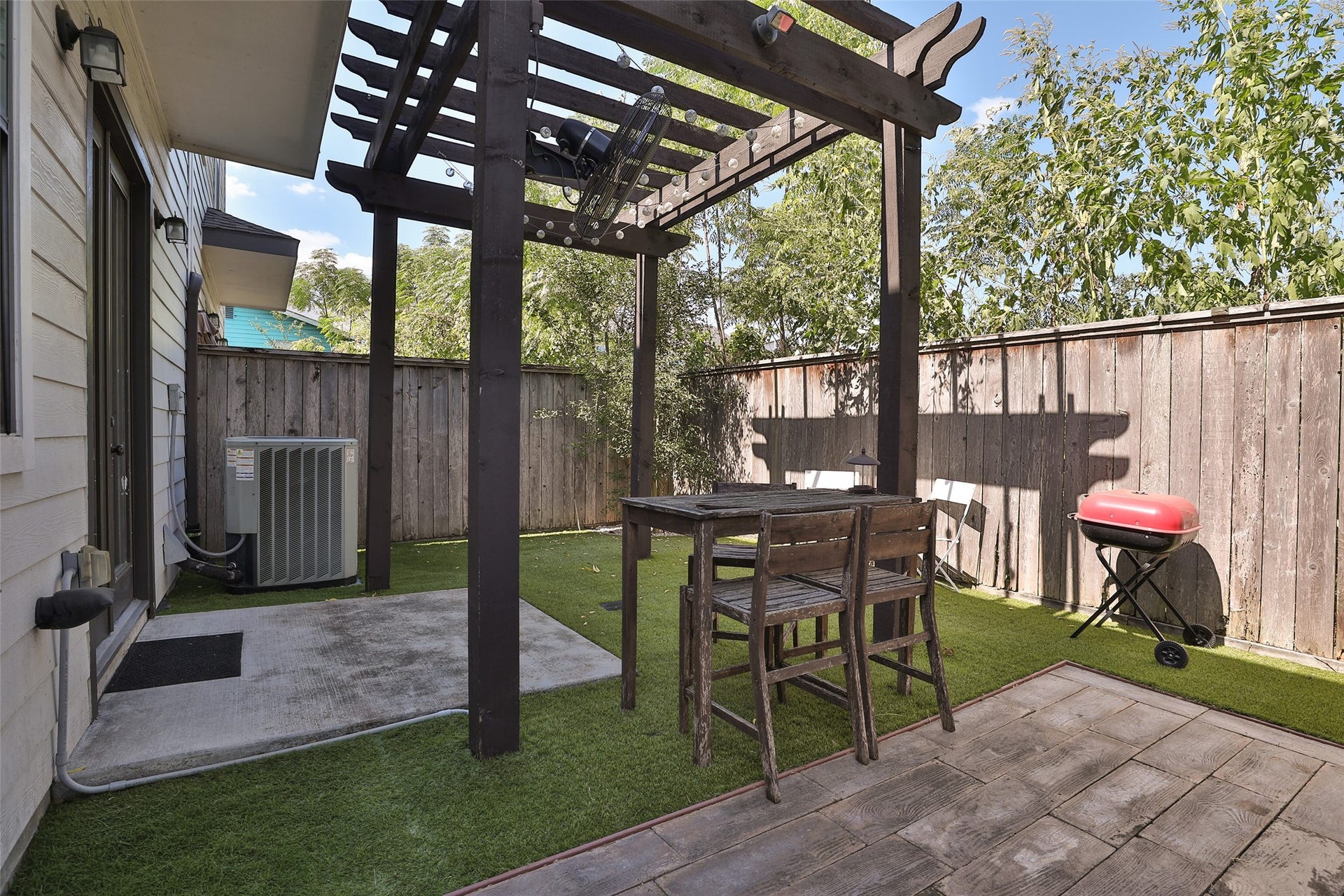 1112 Bingham Street, Houston, TX 77007 Charming backyard patio with a wooden pergola, perfect for outdoor dining and entertaining, complete with a barbecue grill and lush greenery for a serene atmosphere.