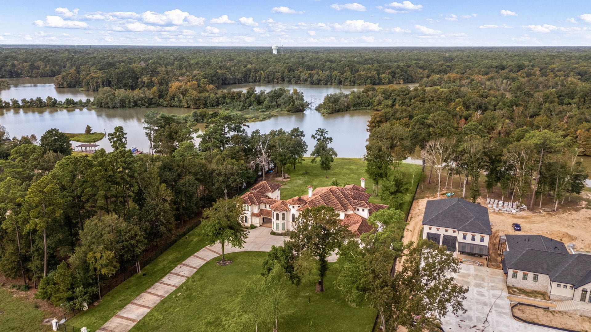 An aerial perspective highlights the property's stunning, expansive acreage and its close proximity to a beautiful, serene lake. Surrounded by lush, mature trees, this private estate offers a perfect blend of secluded luxury and scenic waterfront views.