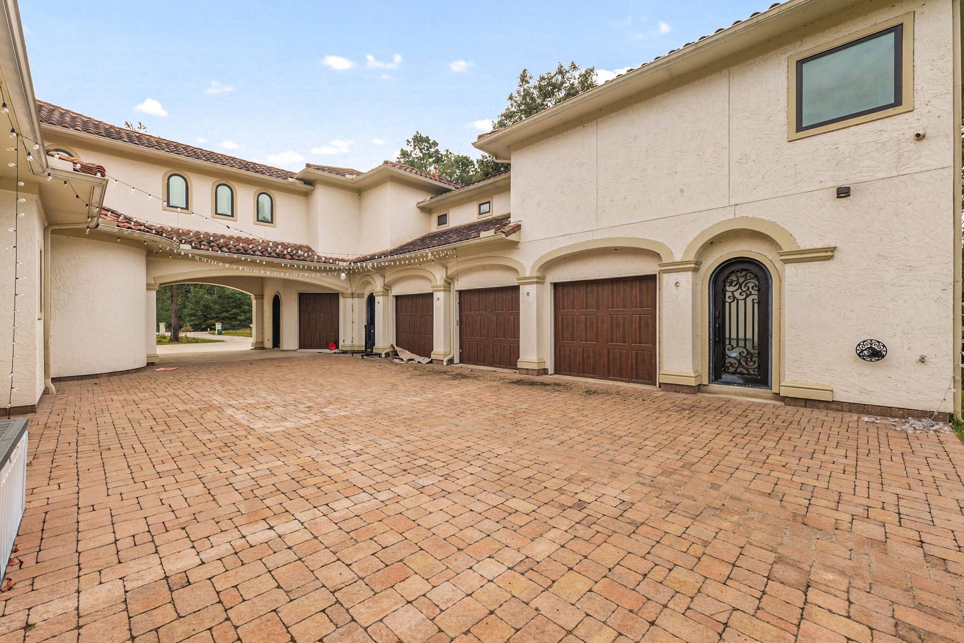 A massive brick-paver motor court and a spacious 6-car garage offer ultimate convenience and plenty of space for vehicle storage. The elegant porte-cochre architectural design seamlessly connects the wings of the estate while maintaining the home's striking Mediterranean aesthetic.