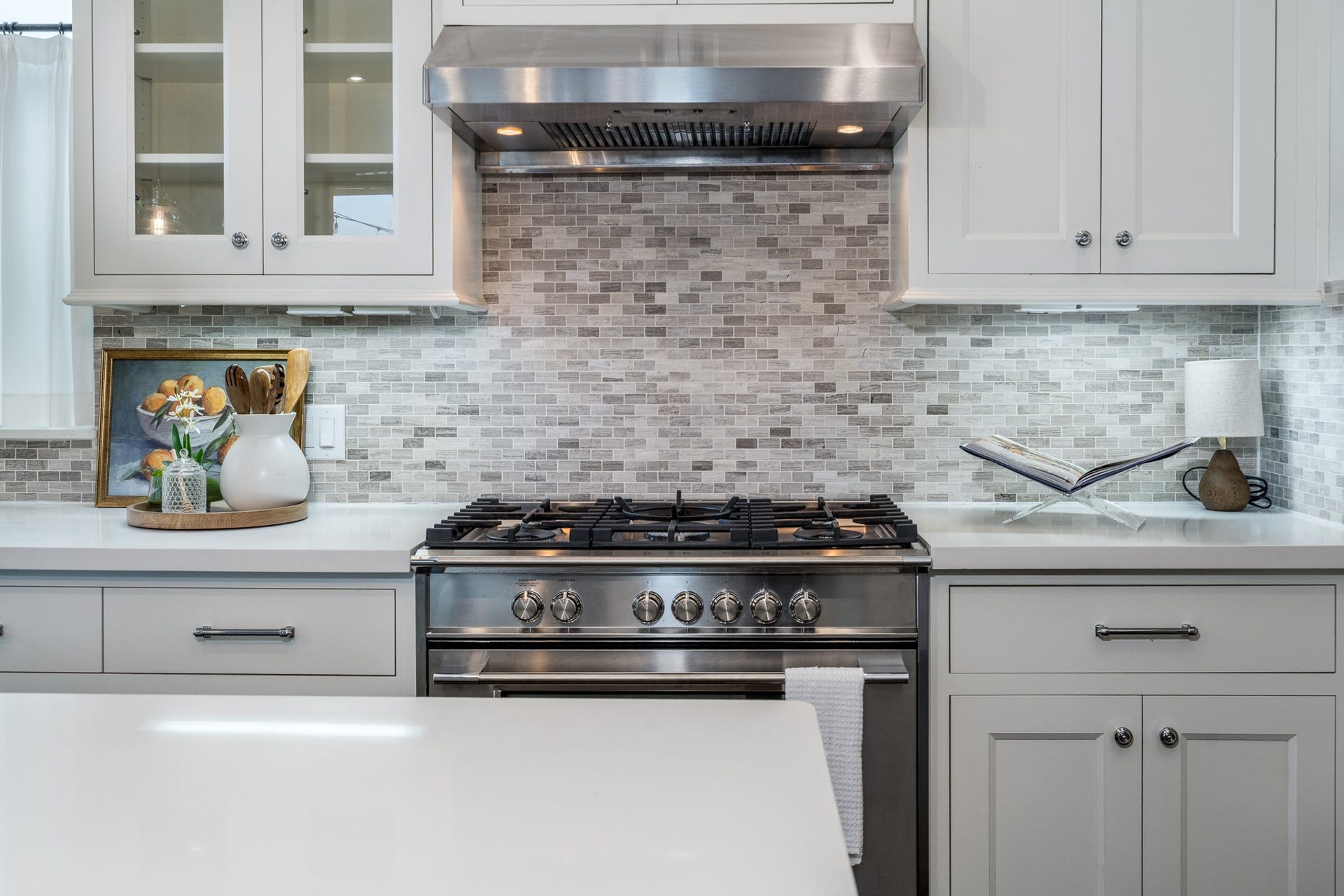 8624 Emnora Lane, Houston, TX 77080 A six burner gas cooktop surrounded by beautiful backsplash and white cabinetry.