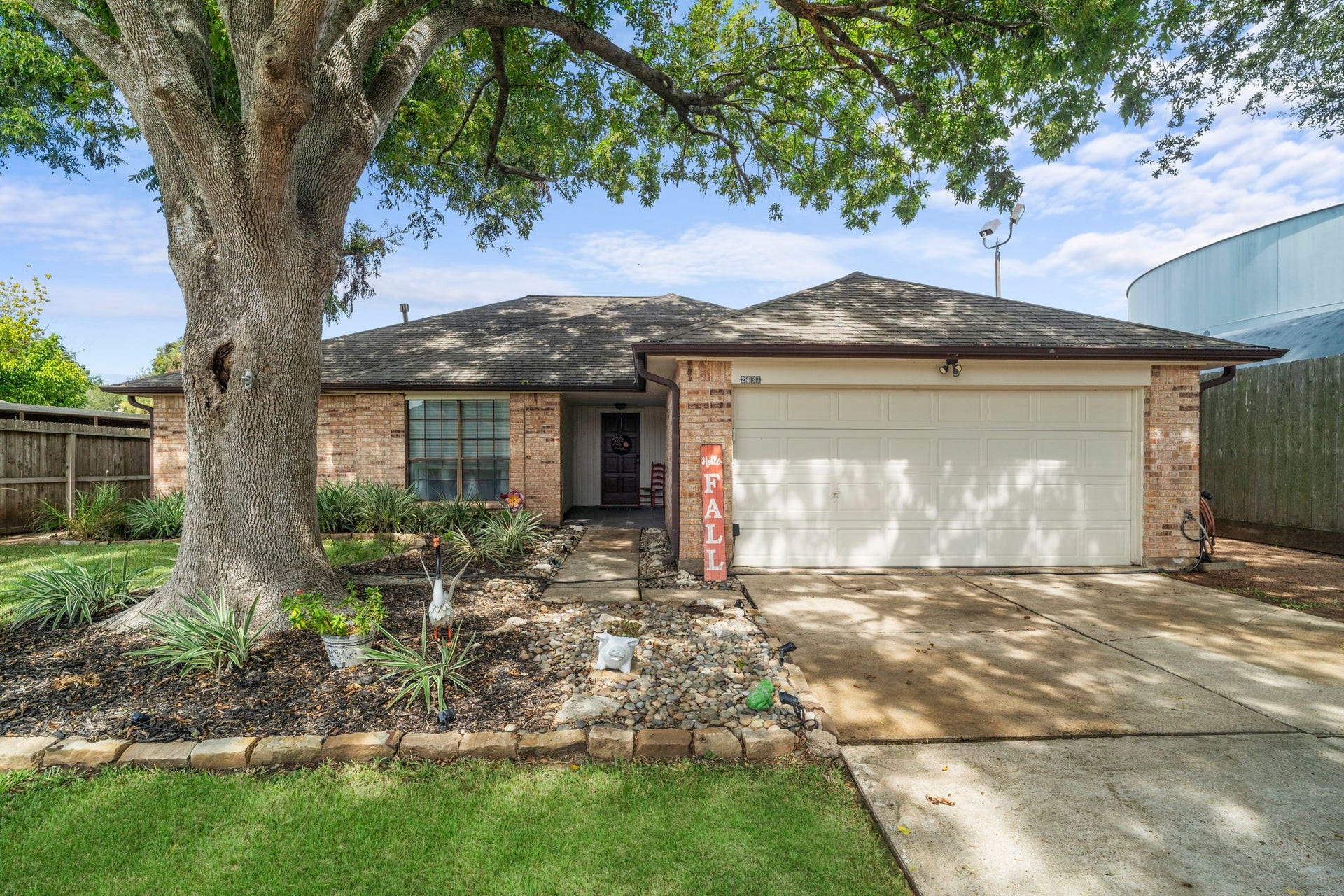 2437 Willow Bend Drive, Richmond, TX 77406 Charming single-story brick home with a welcoming two-car garage and a beautifully landscaped front yard, shaded by a majestic tree.