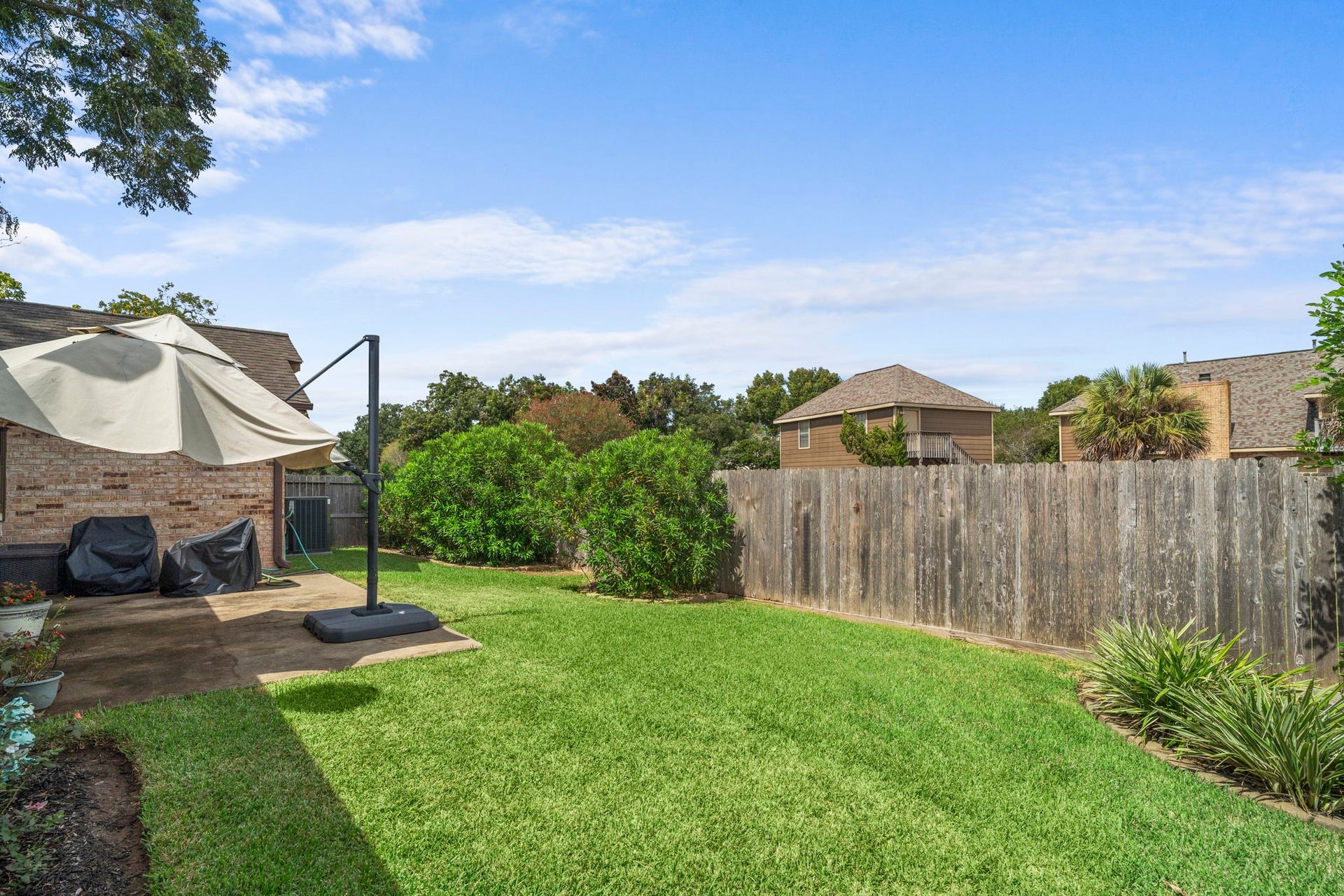 2437 Willow Bend Drive, Richmond, TX 77406 Spacious backyard with lush green lawn, perfect for outdoor activities, featuring a cozy patio area and privacy fence.