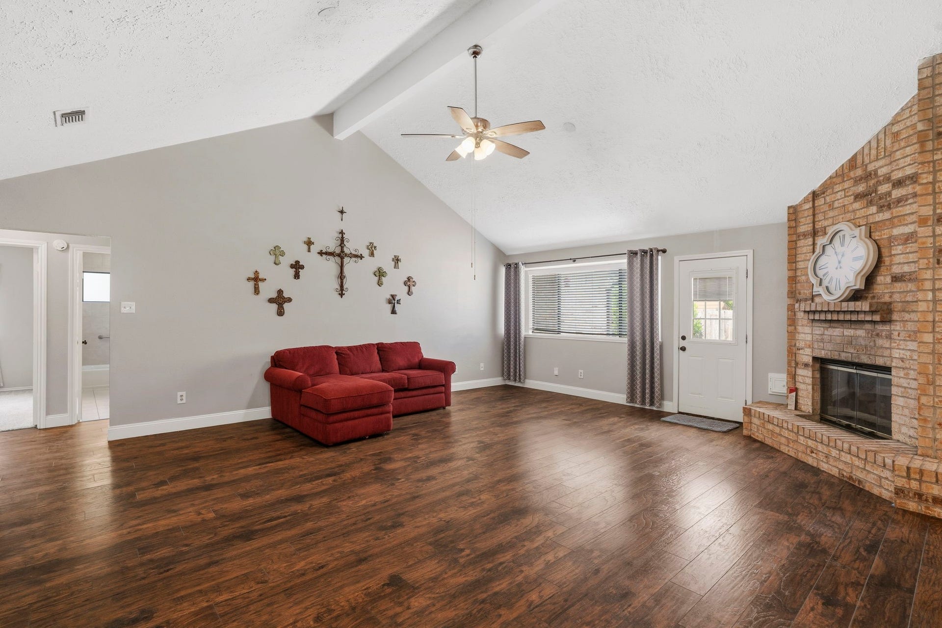2437 Willow Bend Drive, Richmond, TX 77406 Spacious living room featuring vaulted ceilings, a cozy brick fireplace, and elegant laminate wood flooring, perfect for family gatherings.