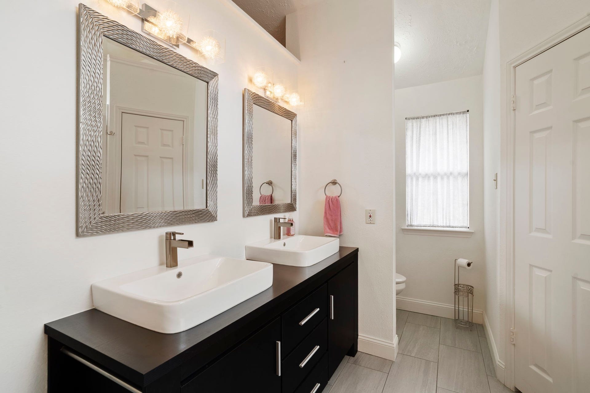 2437 Willow Bend Drive, Richmond, TX 77406 Modern primary bathroom featuring dual sinks with sleek fixtures, elegant framed mirrors, and ample storage beneath.