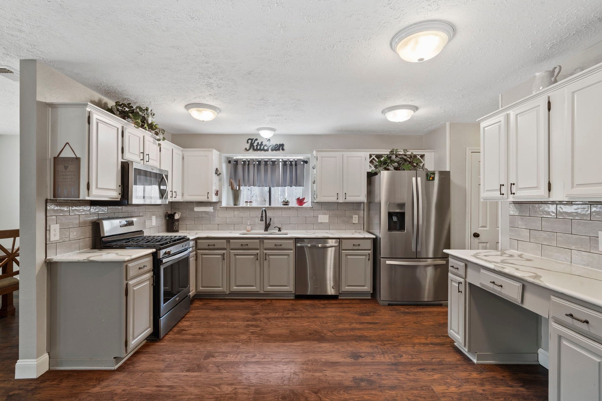2437 Willow Bend Drive, Richmond, TX 77406 Spacious kitchen with modern stainless steel appliances, ample cabinetry, and elegant tile backsplash, complemented by warm laminate wood flooring. Lots of space for prep work in this kitchen.