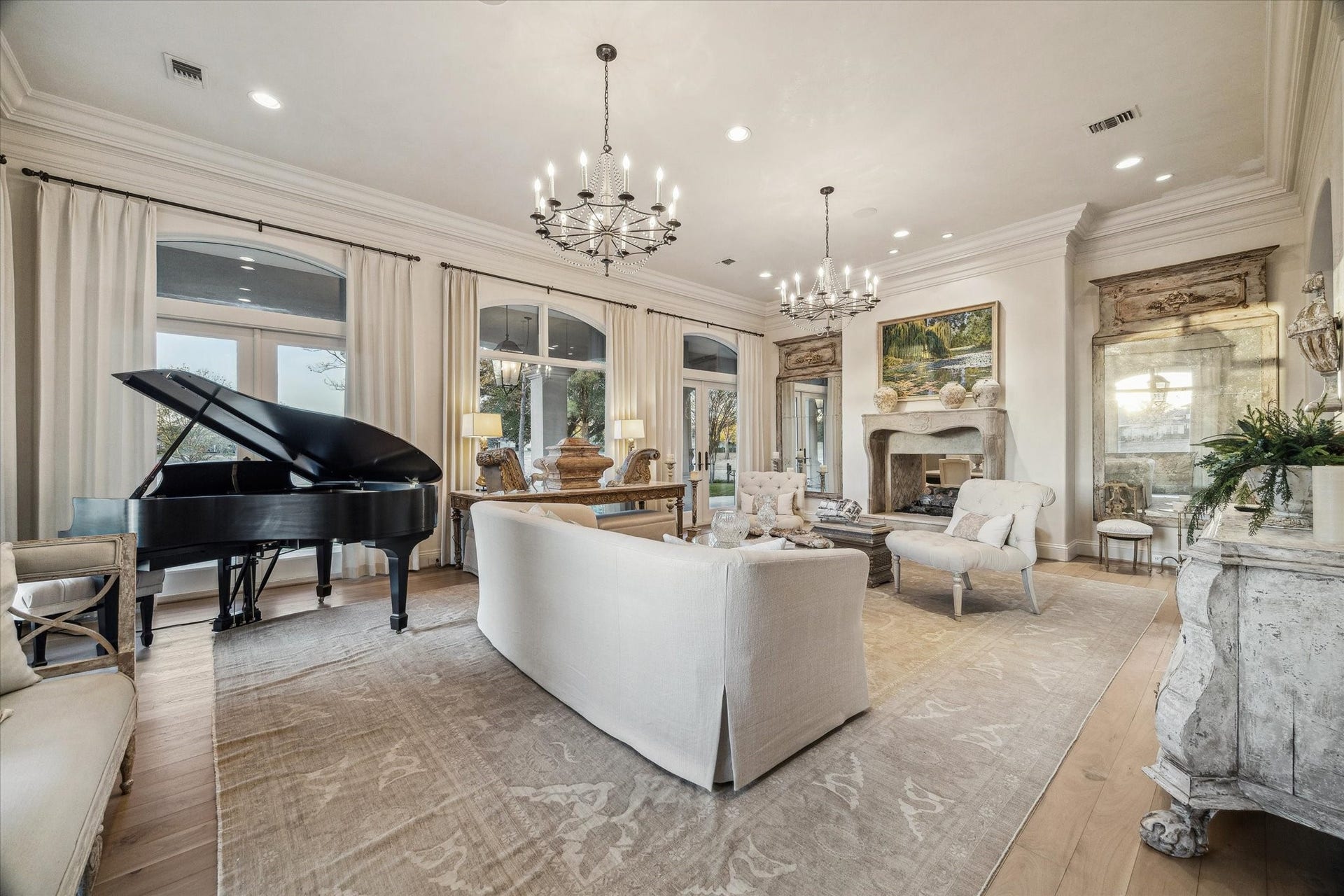 Formal living room featuring expansive windows, elegant lighting, an imported mid century fireplace surround, and an open layout ideal for entertaining. Gorgeous David Iastesta chandeliers.
