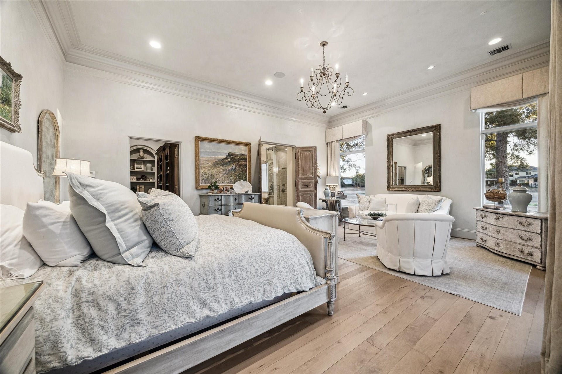 Primary bedroom featuring a spacious layout, elegant lighting, wood flooring, specialty imported doors,and a private sitting area. Lovely private covered lanai off the master bedroom.