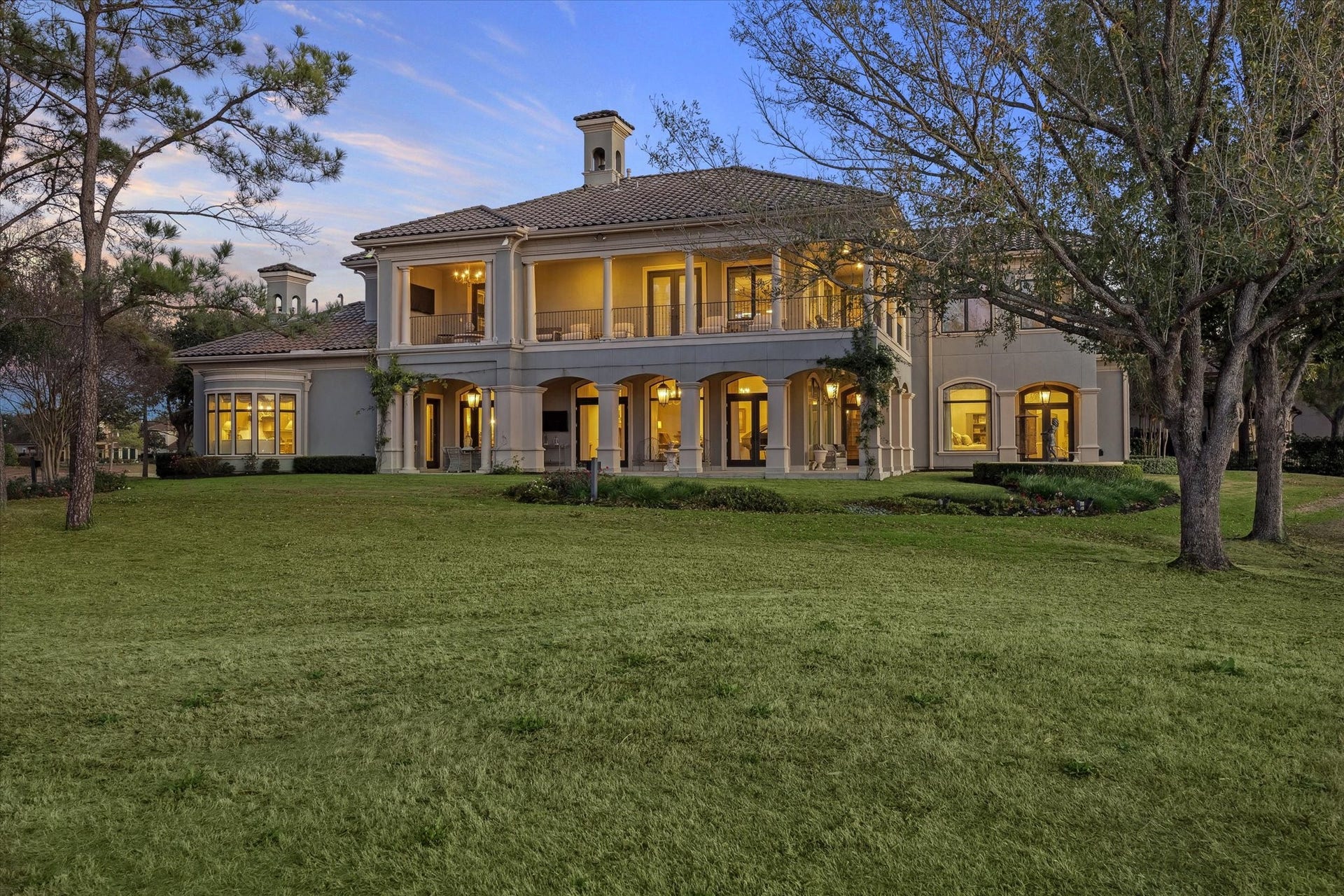 Spacious backyard setting featuring a covered patio, upper balcony and expansive lawn - ideal for indoor-outdoor living.Beautiful fountain with statue on the grounds.