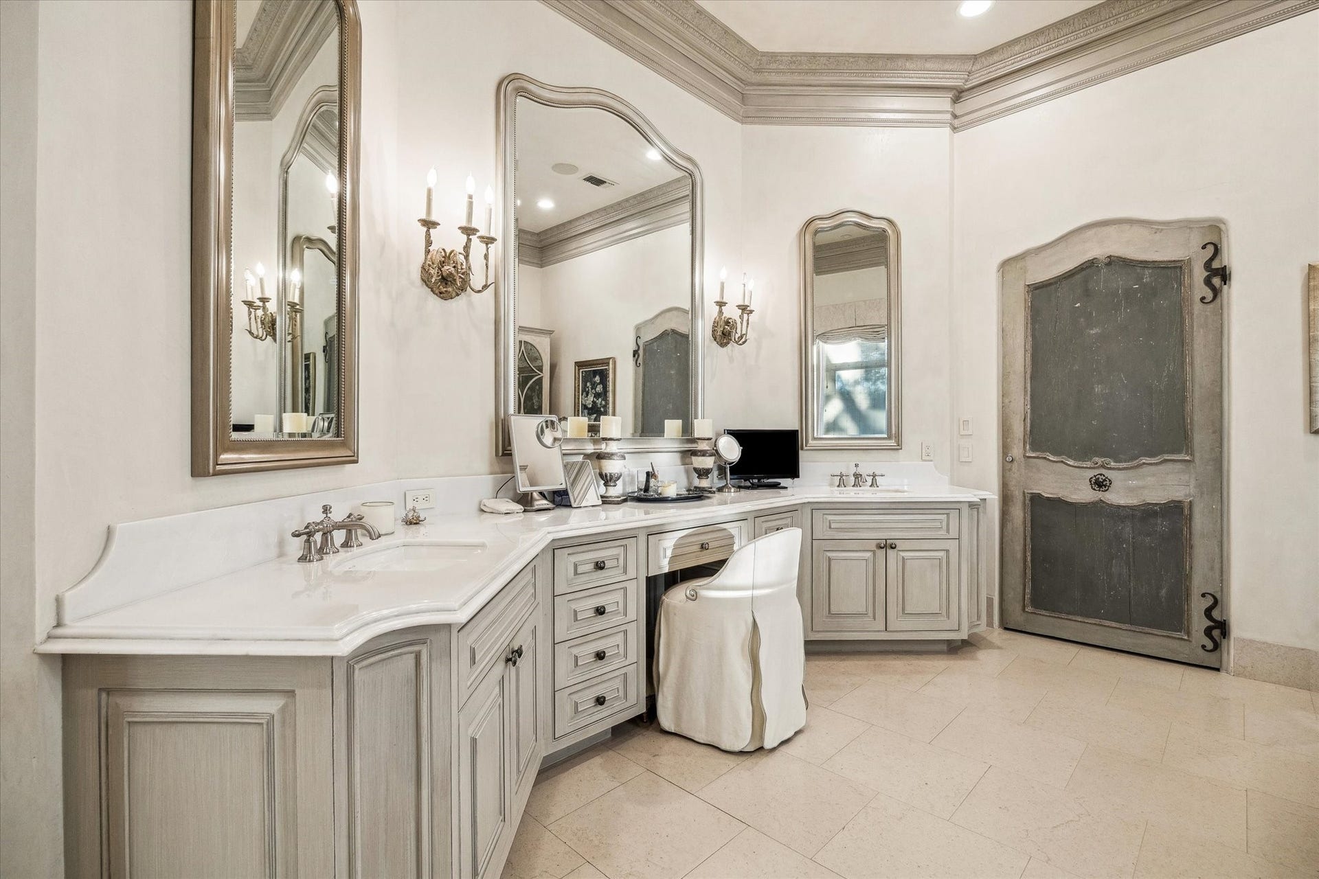 Primary bathroom featuring dual vanities, custom cabinetry, elegant mirrors, marble throughout, and ample storage space.