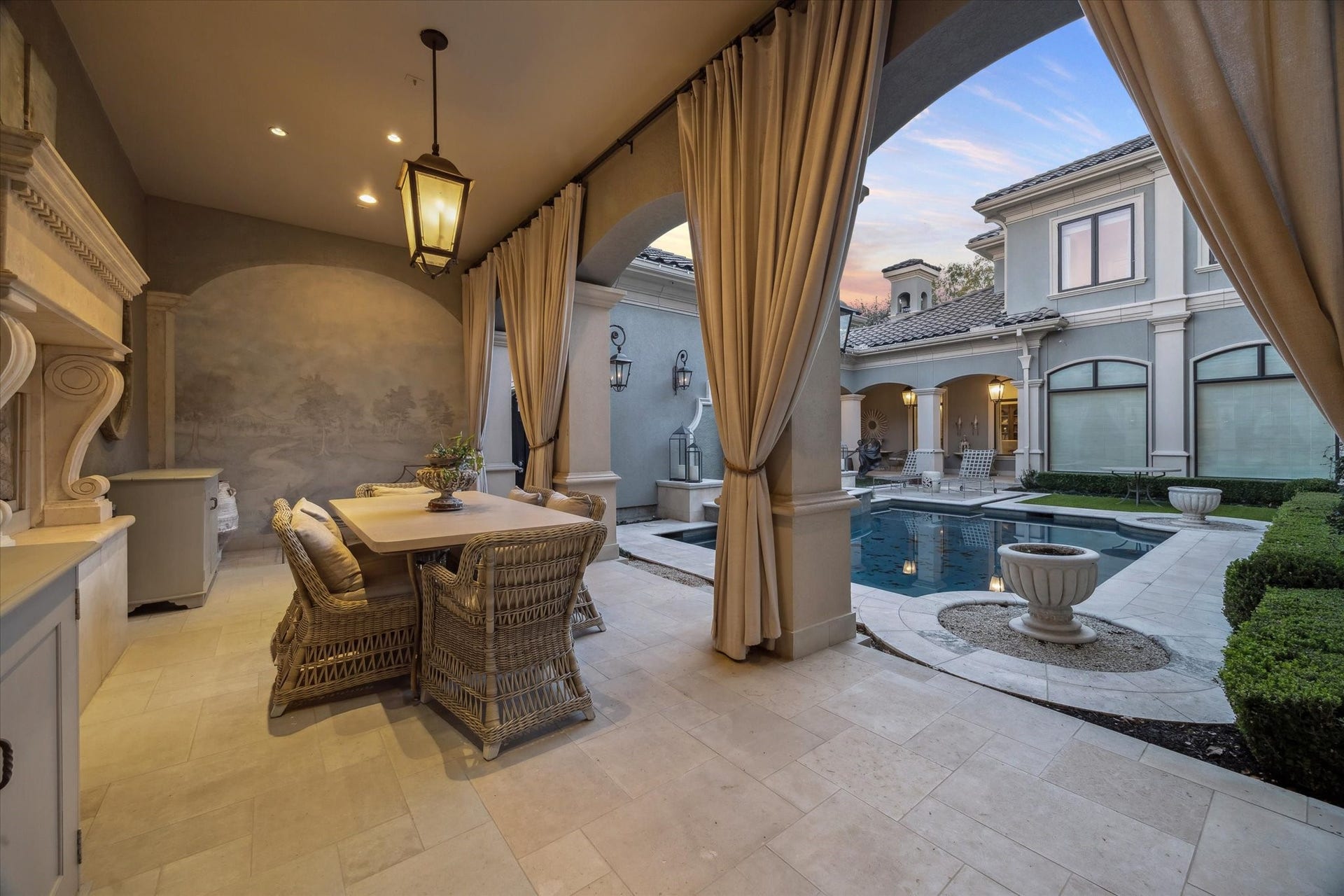 Outdoor living and dining area overlooking the courtyard pool, ideal for entertaining and everyday enjoyment. Gorgeous fireplace and custom mural.