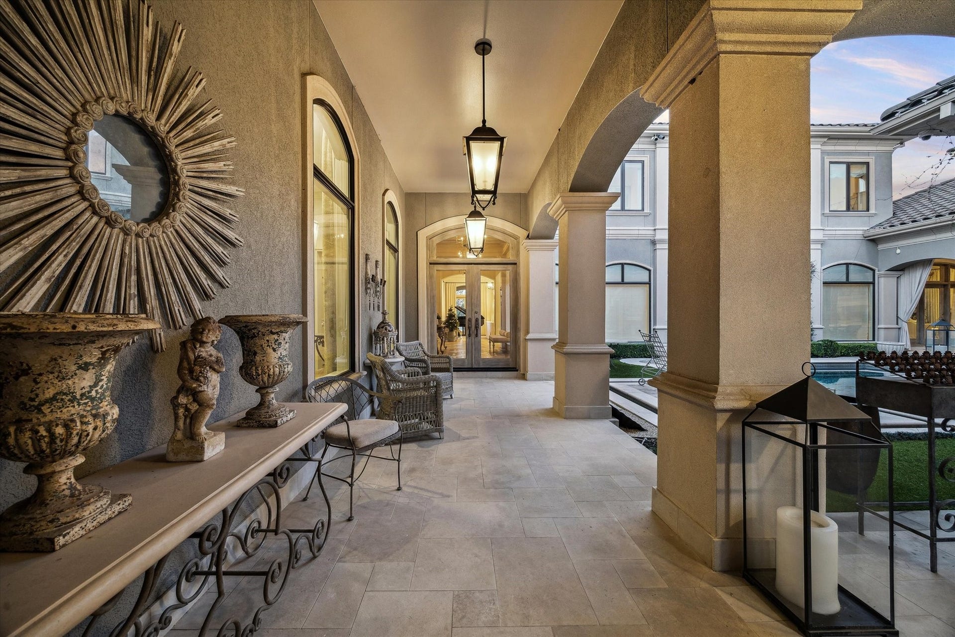 Formal covered entryway featuring elegant architectural details, stone flooring, and a welcoming approach to the home.