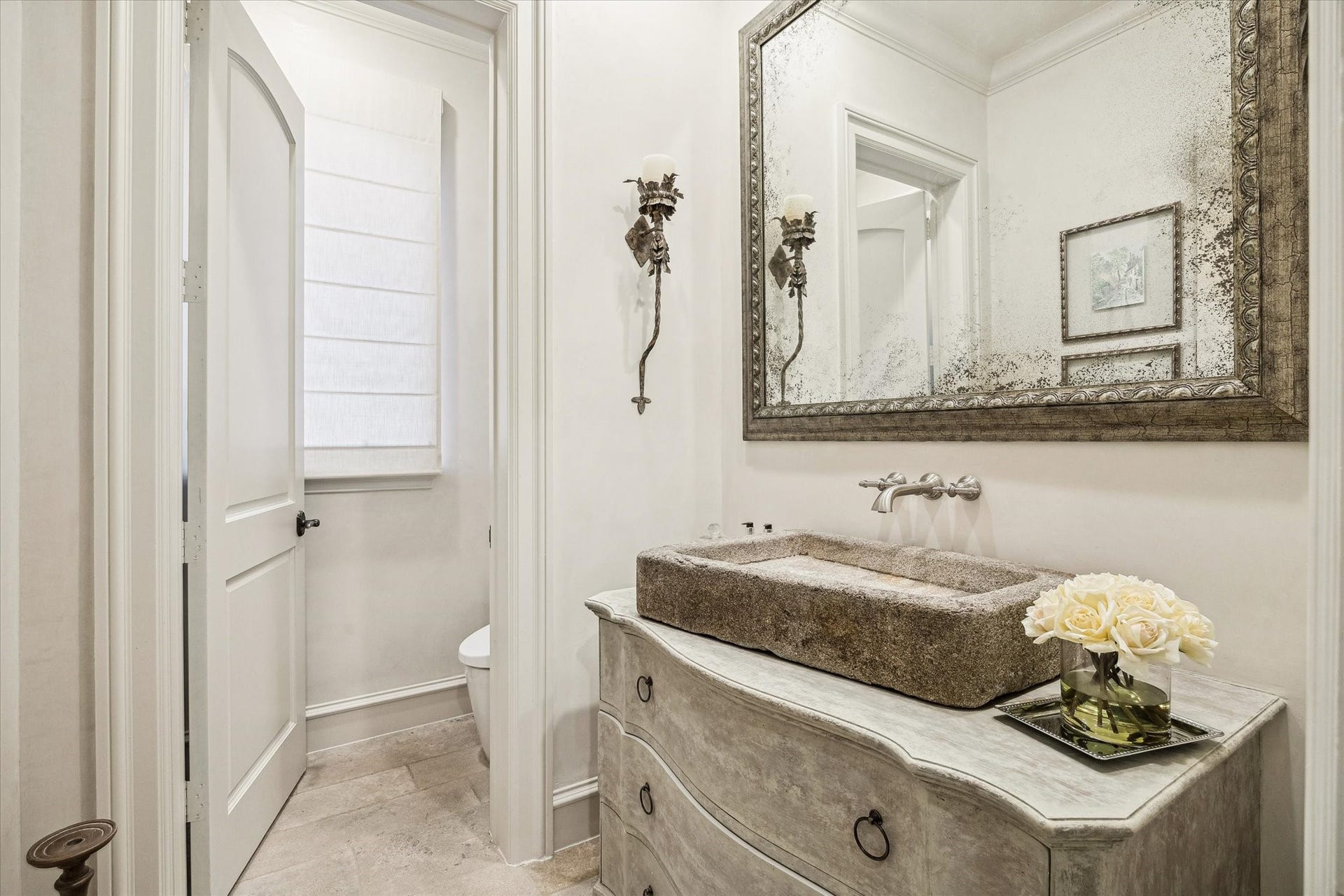 Powder bathroom featuring an imported stone vessel sink, custom vanity, and elegant fixtures, conveniently located off the living room.