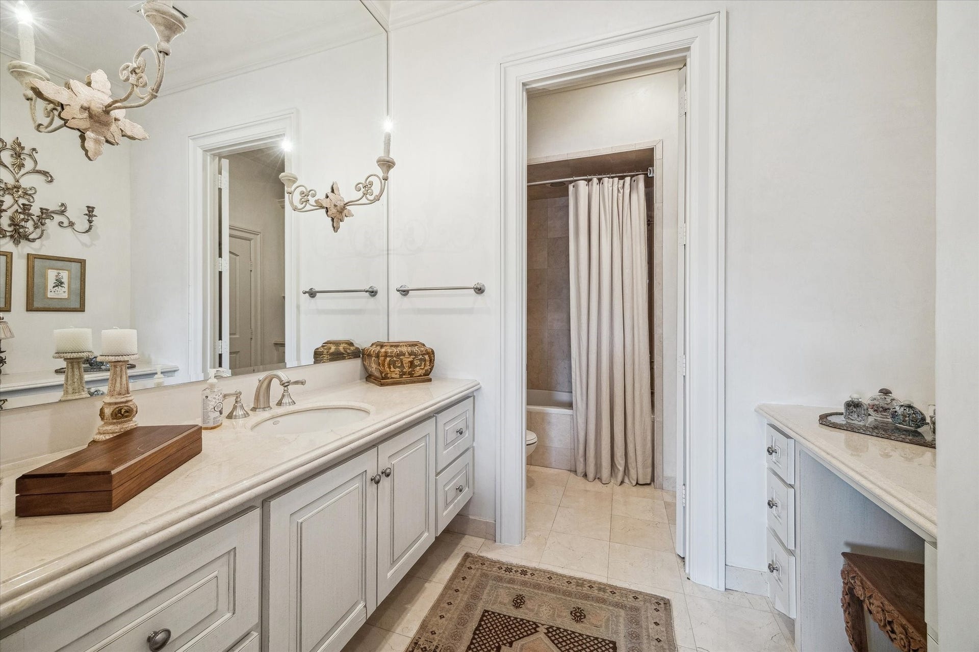 Secondary bathroom featuring a spacious vanity, gorgeous french sconces, dressing vanity, ample storage, and a tub/shower combination with classic finishes.