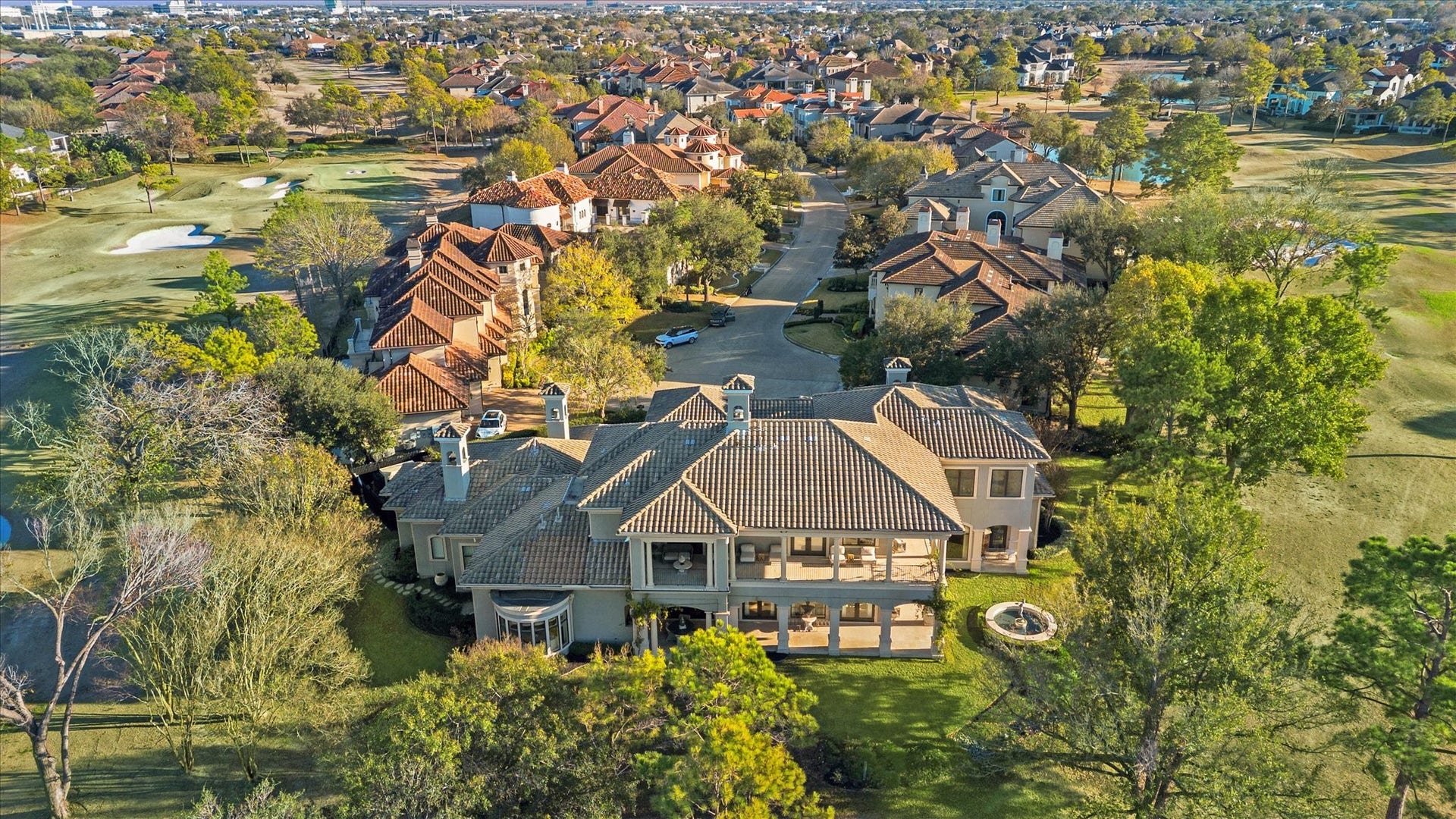 Aerial view highlighting the home's position within the community, showcasing surrounding residences, mature landscaping, and surrounding golf course. Wrap around covered lanais on both floors and a panoramic view of Hole #11 and #17.