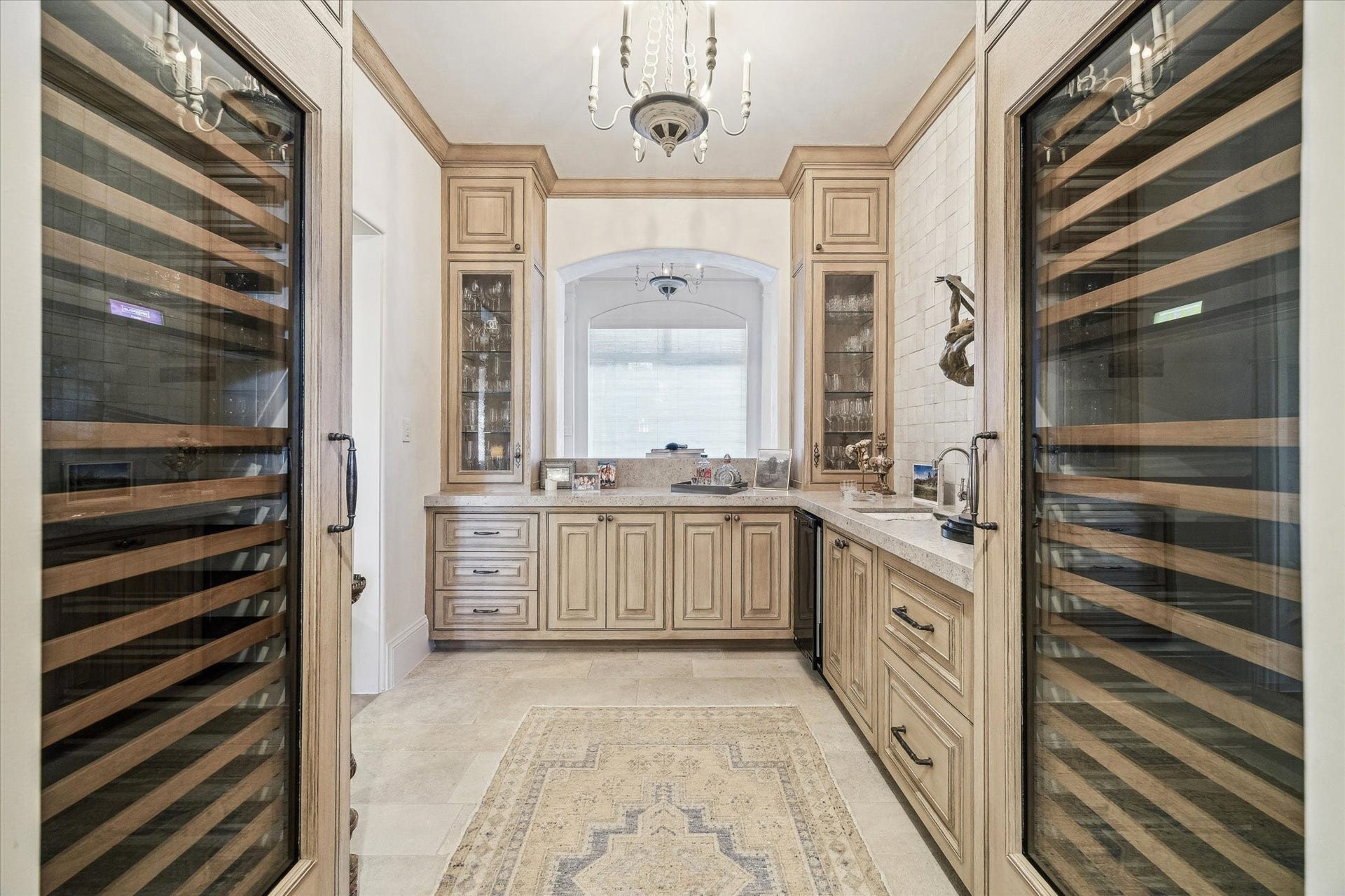Additional view of the wet bar highlighting dual wine refrigerators, custom cabinetry, and glass-front display storage.