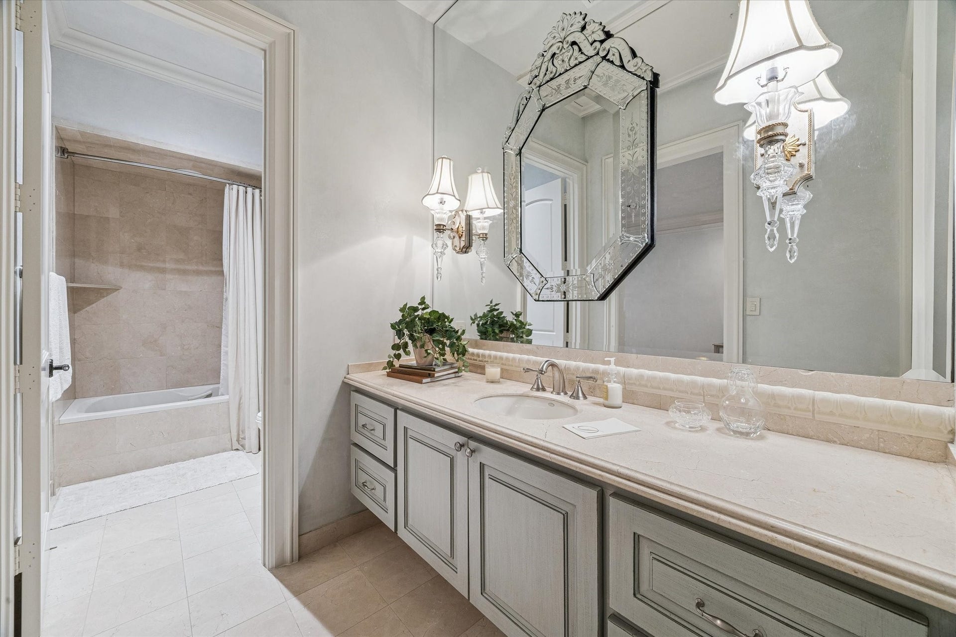 Serene secondary bathroom with floating custom cabinetry and refined finishes. Walk in closet, adjoining bath/shower area and generous counter space.