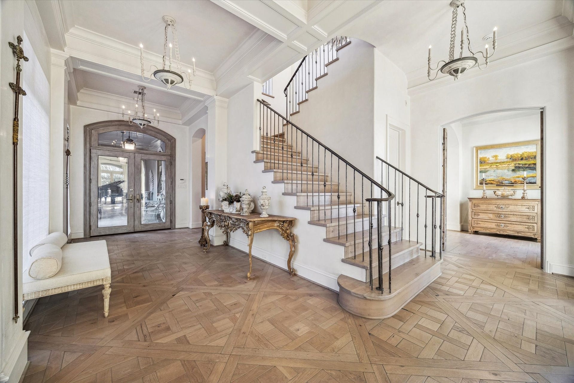 Grand entryway featuring a custom iron staircase, french oak wood flooring, custom millwork, and elegant lighting, creating a striking first impression.
