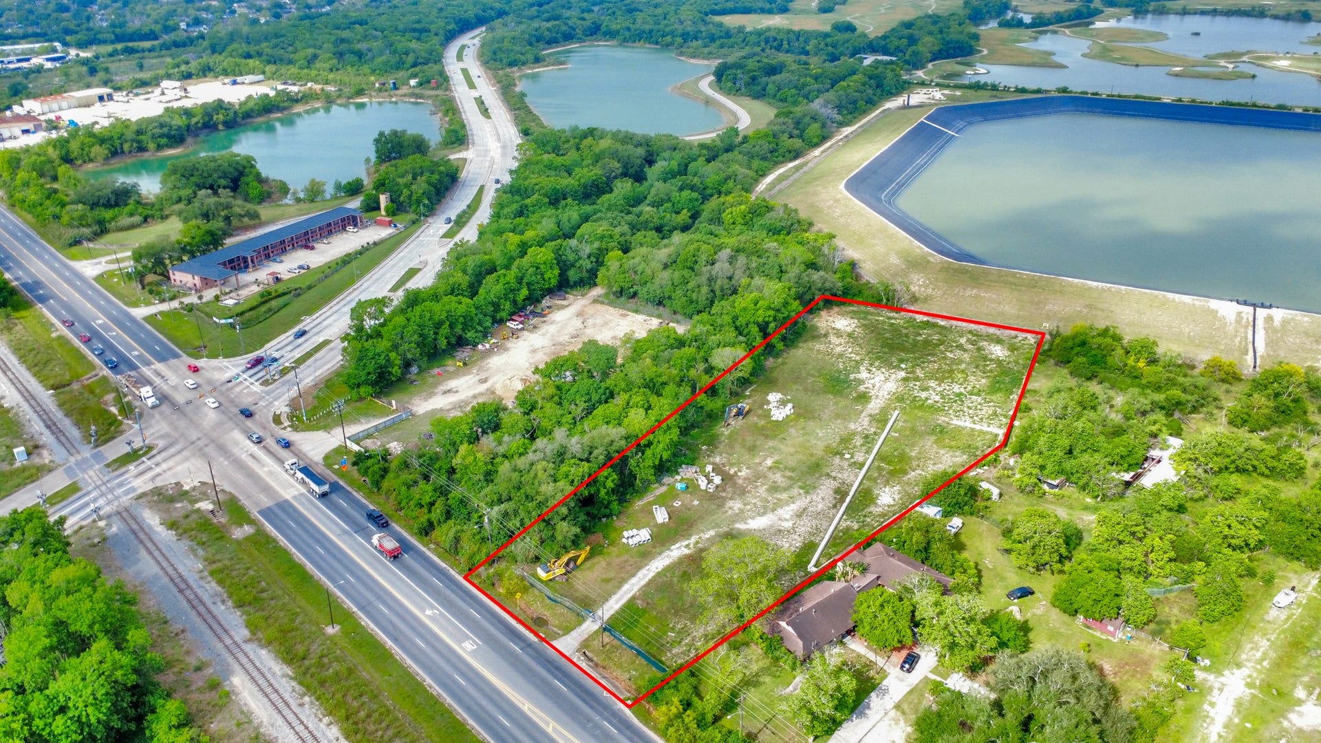 11826 Almeda Road, Houston, TX 77045 This aerial photo shows a rectangular plot of land outlined in red, bordered by greenery and roads. Nearby are water bodies, a busy intersection, and some buildings, indicating a convenient location with natural surroundings.