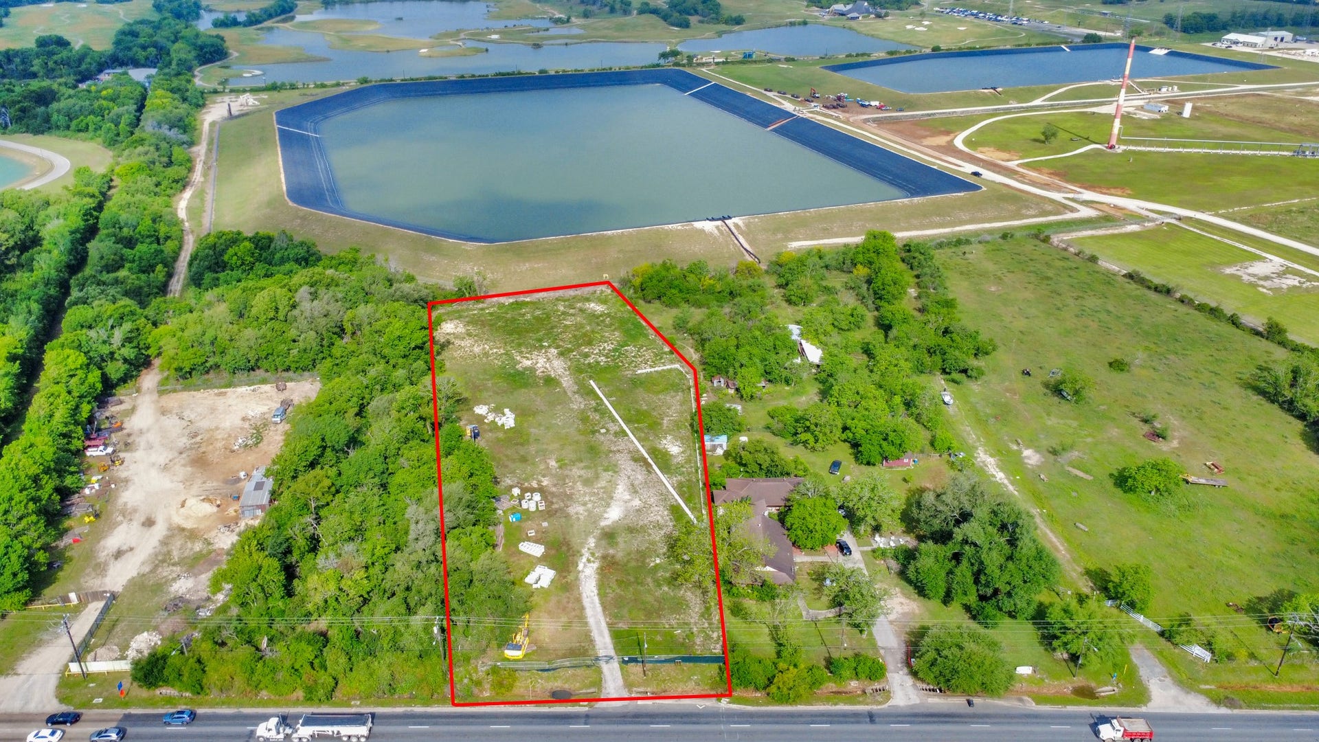 11826 Almeda Road, Houston, TX 77045 This aerial photo showcases a spacious plot of land outlined in red, situated near a large reservoir. The area is surrounded by greenery, with a mix of open space and some trees. Access is via a nearby road, offering potential for development or a private retreat.