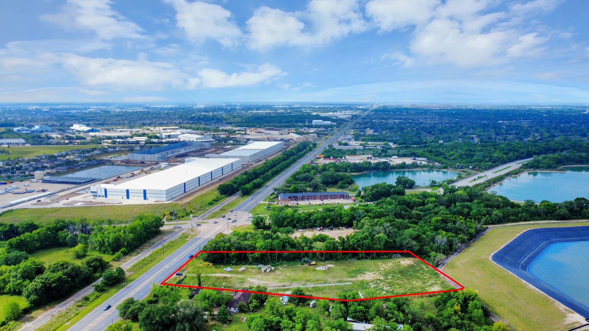 11826 Almeda Road, Houston, TX 77045 This aerial photo showcases a spacious plot of land outlined in red, with lush greenery surrounding it. It is located near a major road, with industrial buildings and water bodies nearby, offering both accessibility and scenic views.