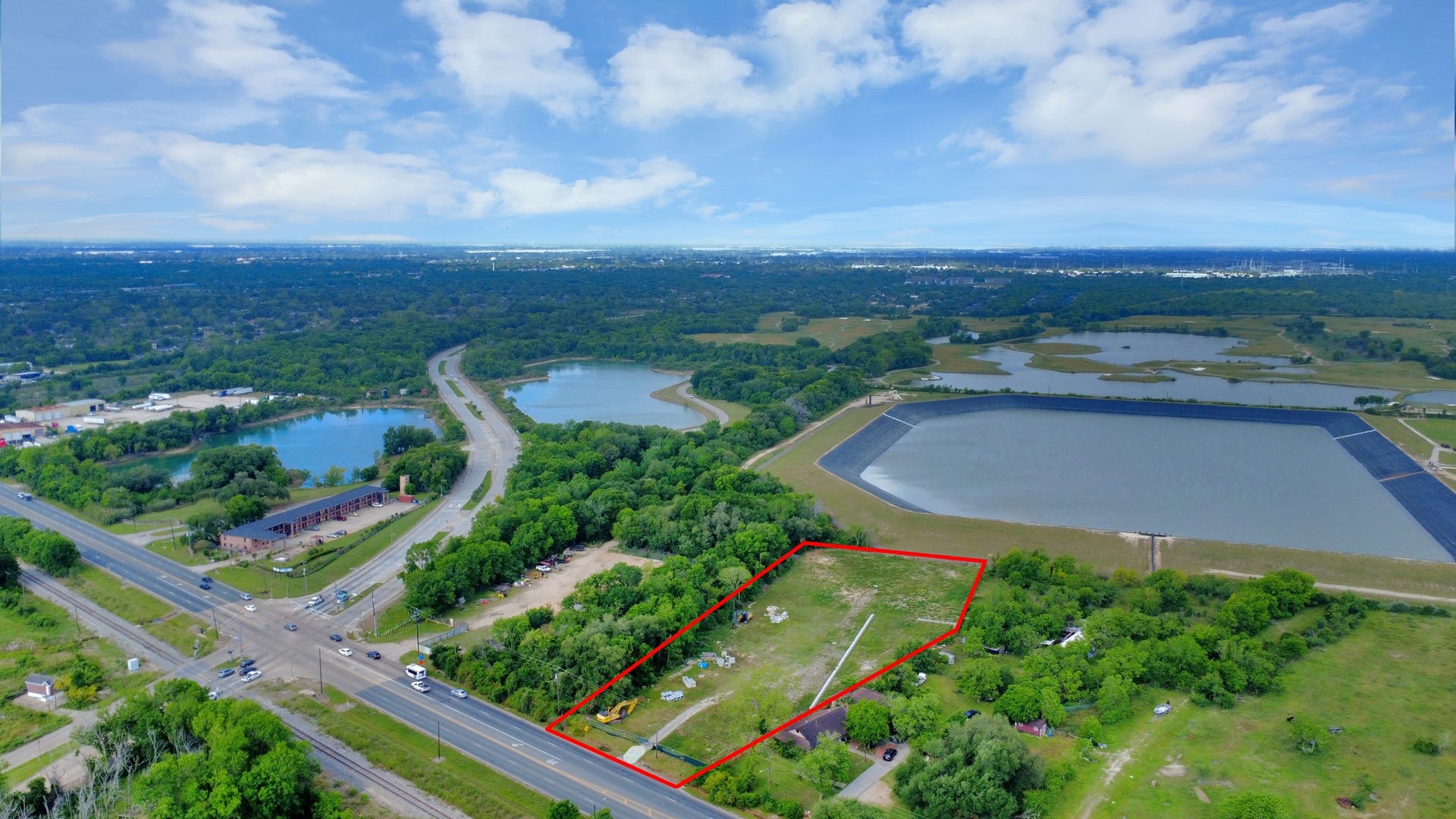 11826 Almeda Road, Houston, TX 77045 This photo showcases a spacious plot of land outlined in red, located near a main road and surrounded by lush greenery. It offers proximity to a large water reservoir and has easy access to nearby amenities. Ideal for buyers seeking a serene yet accessible location.