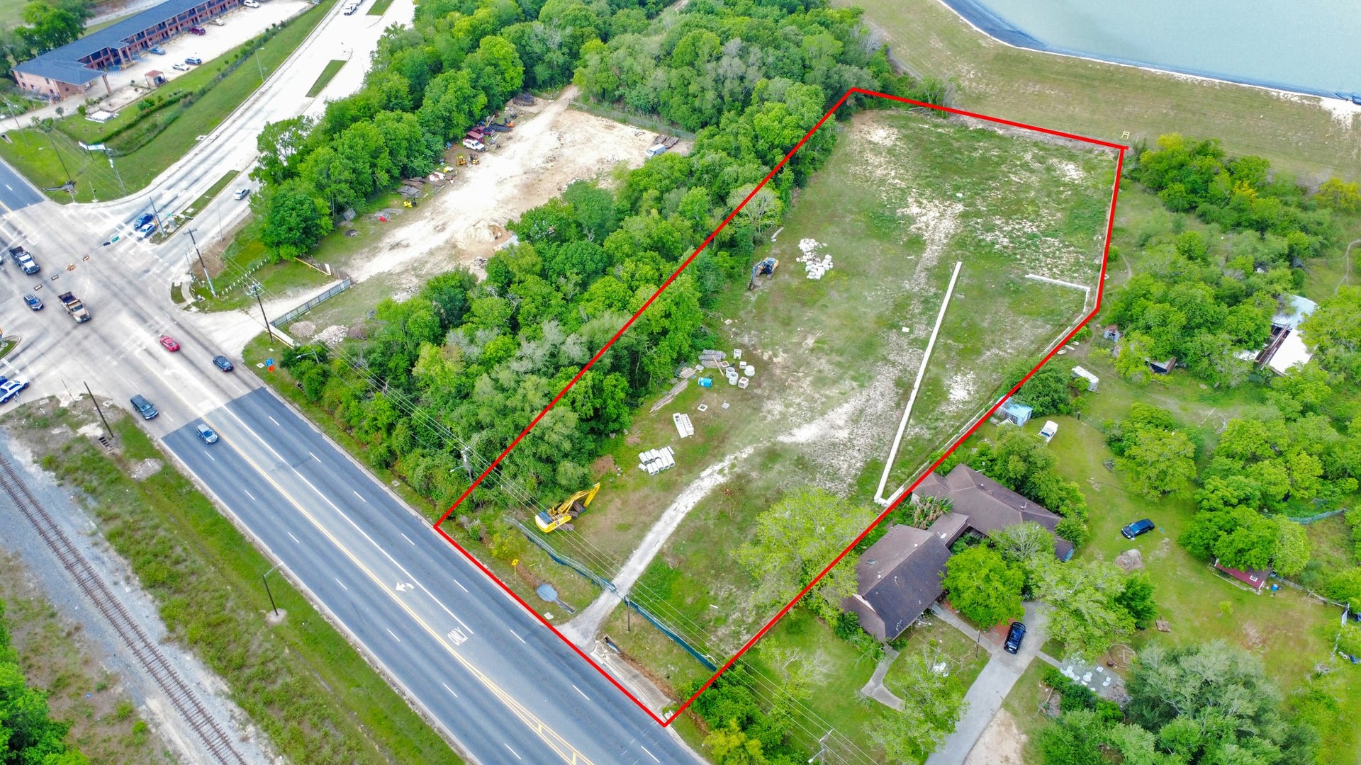 11826 Almeda Road, Houston, TX 77045 This aerial photo showcases a large, rectangular plot of land bordered in red, featuring a mix of open space and trees. It includes a house, access to a main road, and proximity to a body of water, making it ideal for development or a private residence.