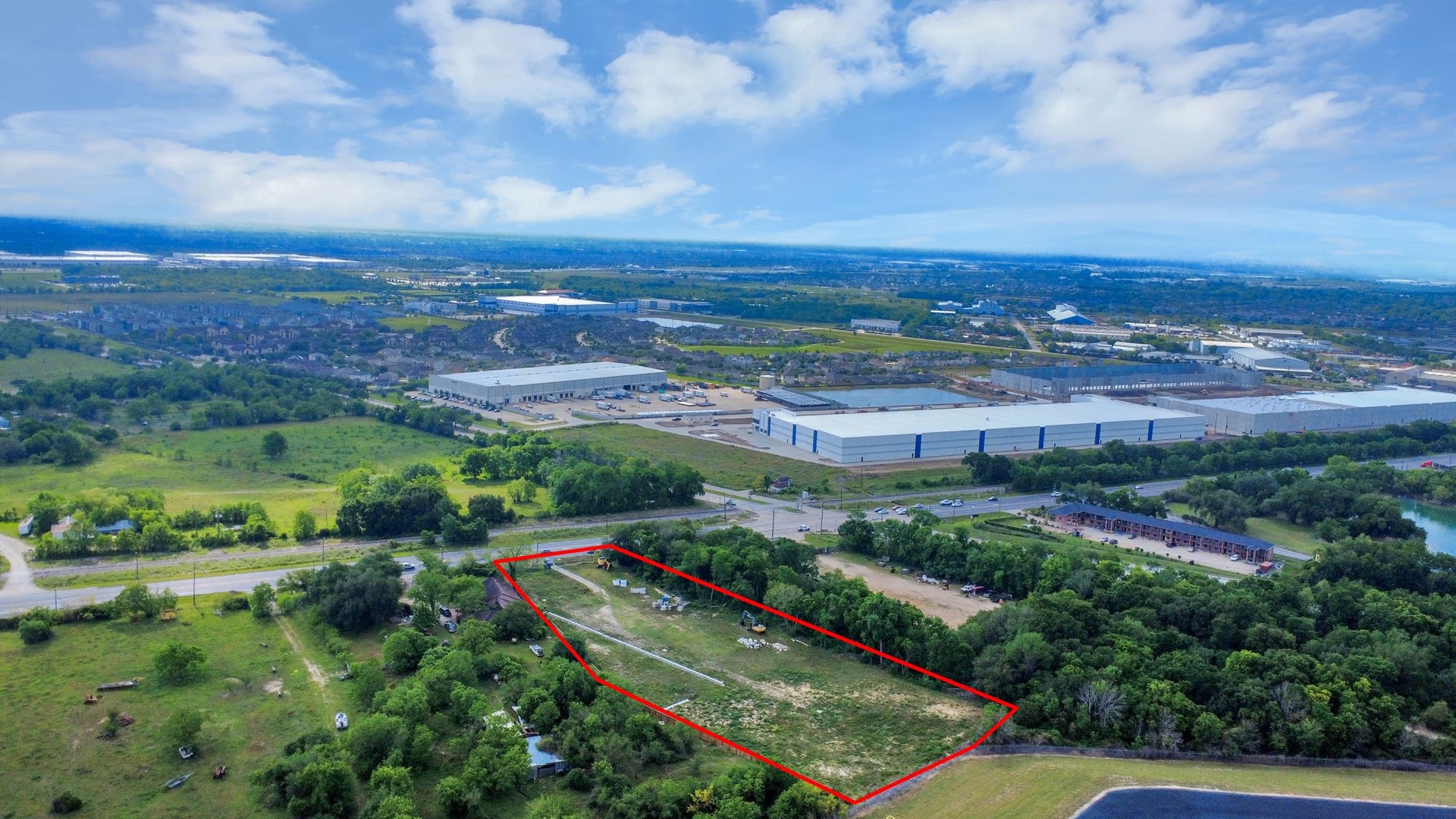 11826 Almeda Road, Houston, TX 77045 This aerial photo showcases a plot of land outlined in red, situated in a semi-rural area with industrial buildings nearby. The property is surrounded by greenery and has road access, offering a blend of natural and developed surroundings.
